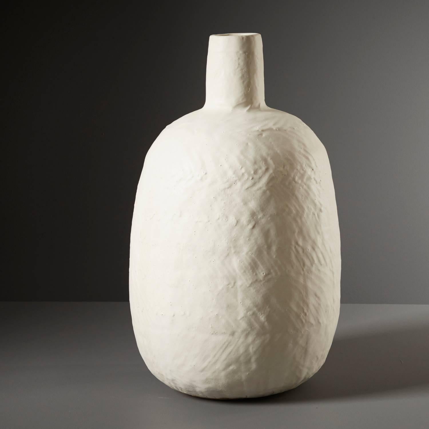 Daniel Reynold’s ‘Large White Bottle’ is a striking decorative vessel crafted to complement any interior. Hand built in stoneware clay, this modern piece is an assembly of depth and texture achieved by applying dolomite glaze: a calcium magnesium