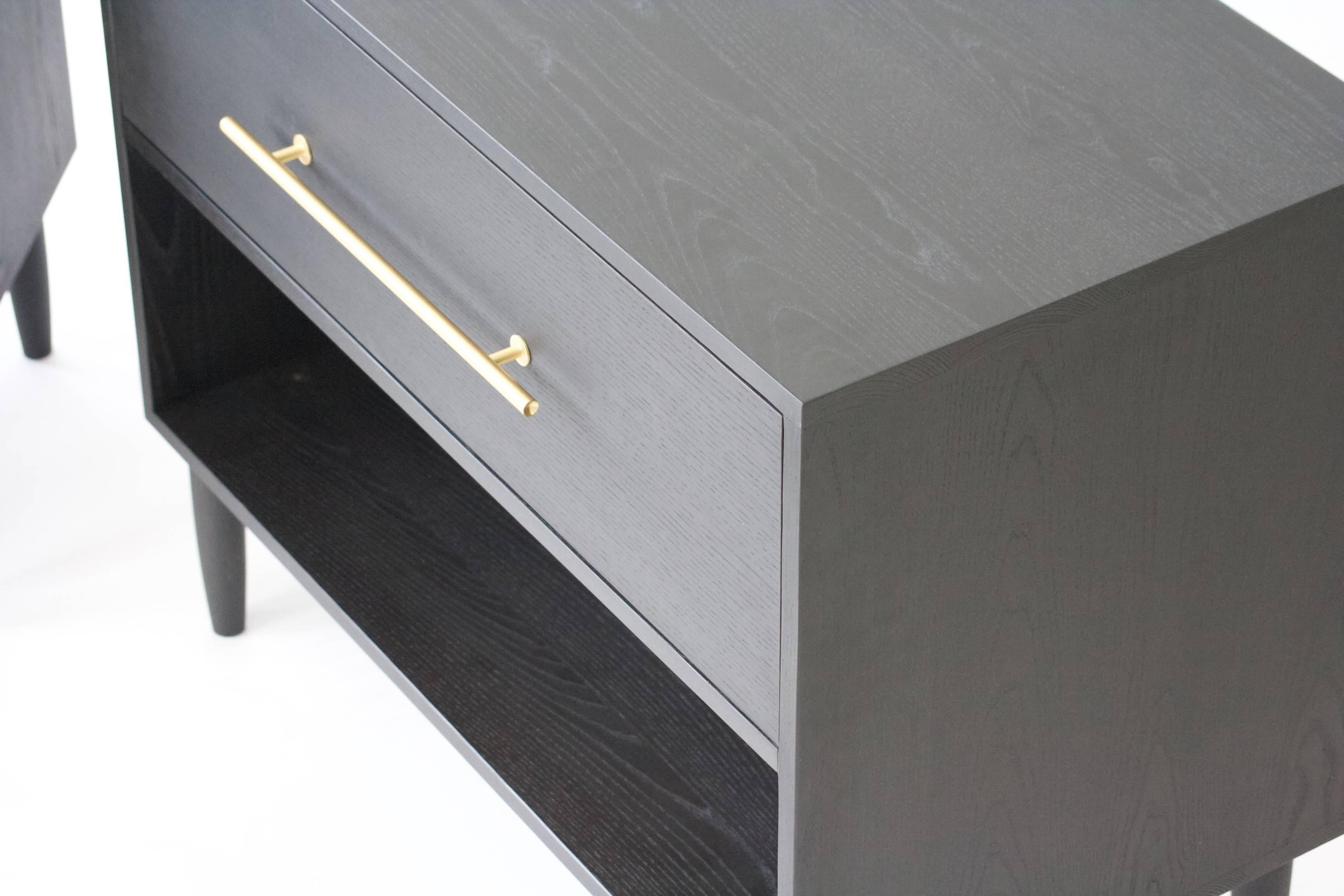 Modern solid wood nightstands with blackened finish. Feature premium drawer hardware and a solid wood dovetailed drawer box. The brass hardware pops off the black Ash case. The solid wood carcass sits on hand-turned legs.