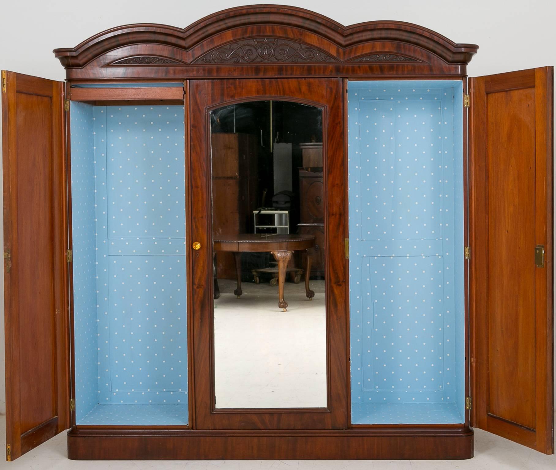 Mahogany three-door gentleman's wardrobe.
Featuring very highly flamed mahogany doors.
A lovely triple domed top with deeply carved inserts.
The left and right hand side for hanging and the centre section having mahogany drawers and mahogany