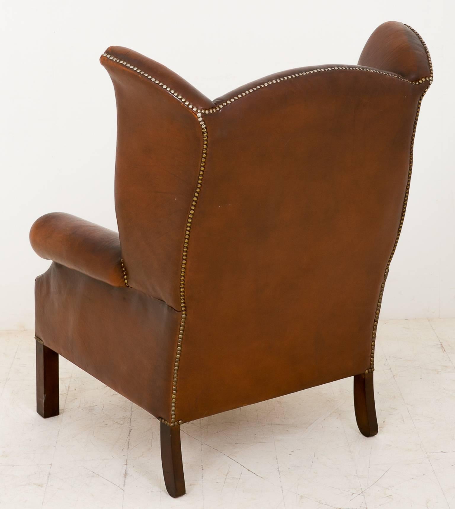 Pair of leather wing chairs with Georgian influences.
Standing on square mahogany legs.
The leather work having brass stud work.
These chairs are extremely comfortable.

Size:

Height 42" (79cm)
Width 31" (79cm)
Depth 25"