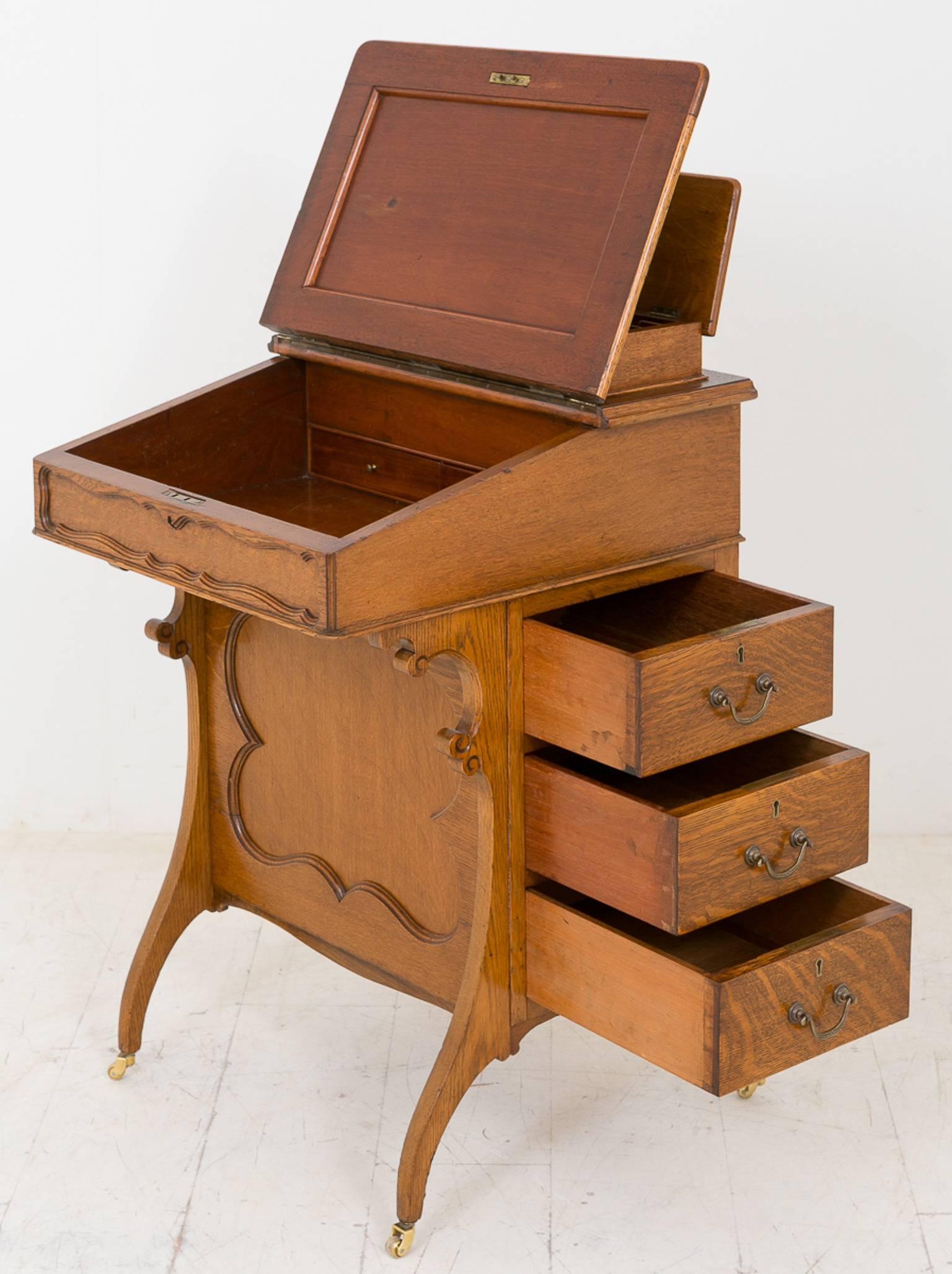 Oak Arts and Crafts style davenport, standing on swept legs with brass castors.
Three working mahogany lined drawers to the right hand side.
The leather covered writing slope opens to reveal two drawers.
The top section fitted with letter trays