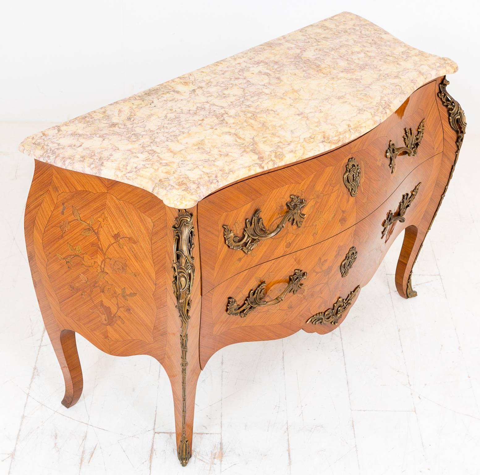 Here we have a very nice quality French walnut commode, standing on swept legs with gilt brass toes and shoulders.
The two oak lined marquetry drawers featuring very ornate gilt and brass handles and escutcheons.
The sides of the commode also