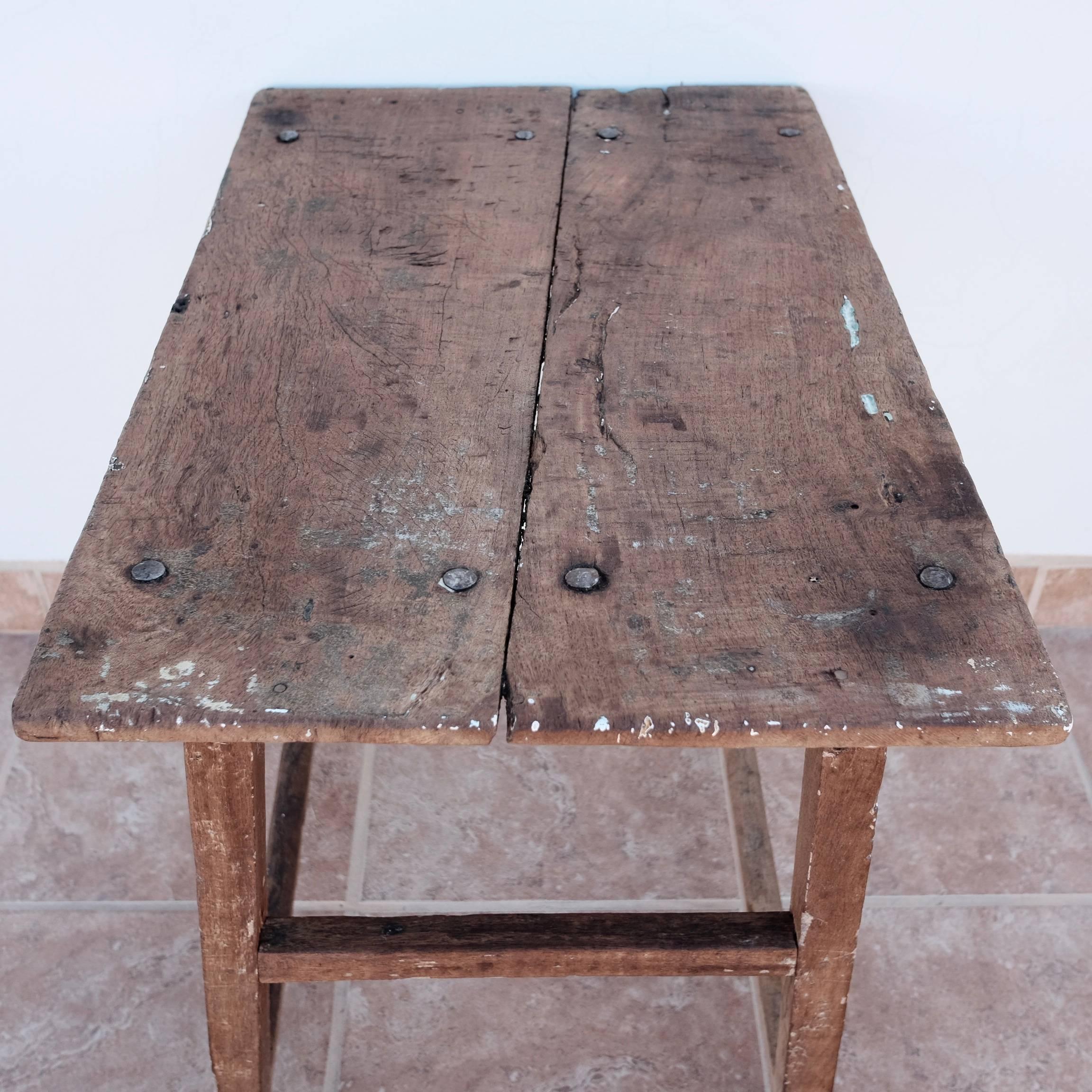 Rare, colonial era mesquite hardwood console table with original hardware and peg assembly in its original state. Tabletop is composed of two planks cut in an interesting diagonal fashion. Rustic tabletop contains bits of paint or plaster that have