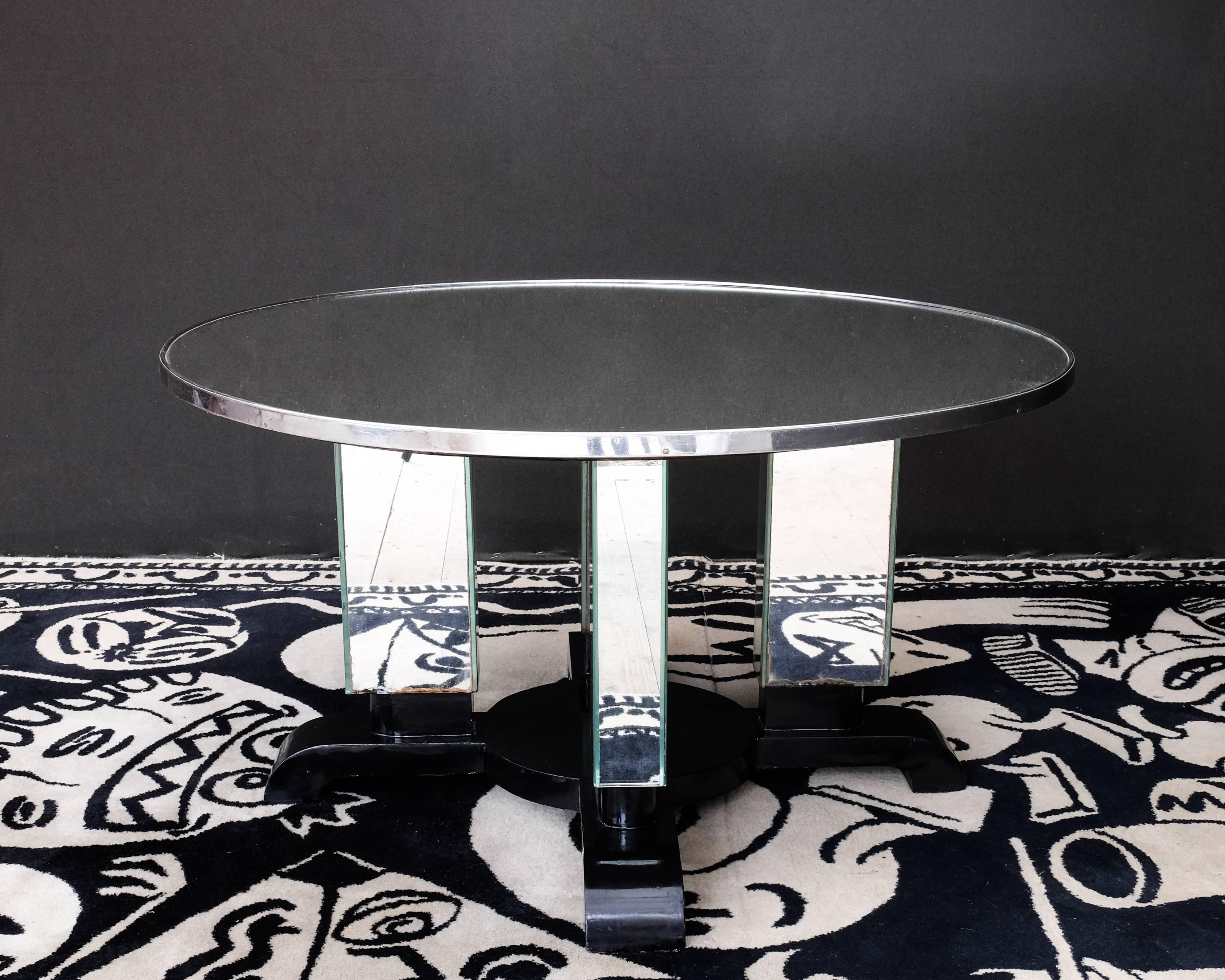 Jules Leleu (1883-1961)
Guéridon model n ° 2563, 1938

Circular top covered with a mirror, surrounded by a patinated satin metal strip resting on a base made up of four rectangular columns plated with mirrors and fixed on a cruciform black