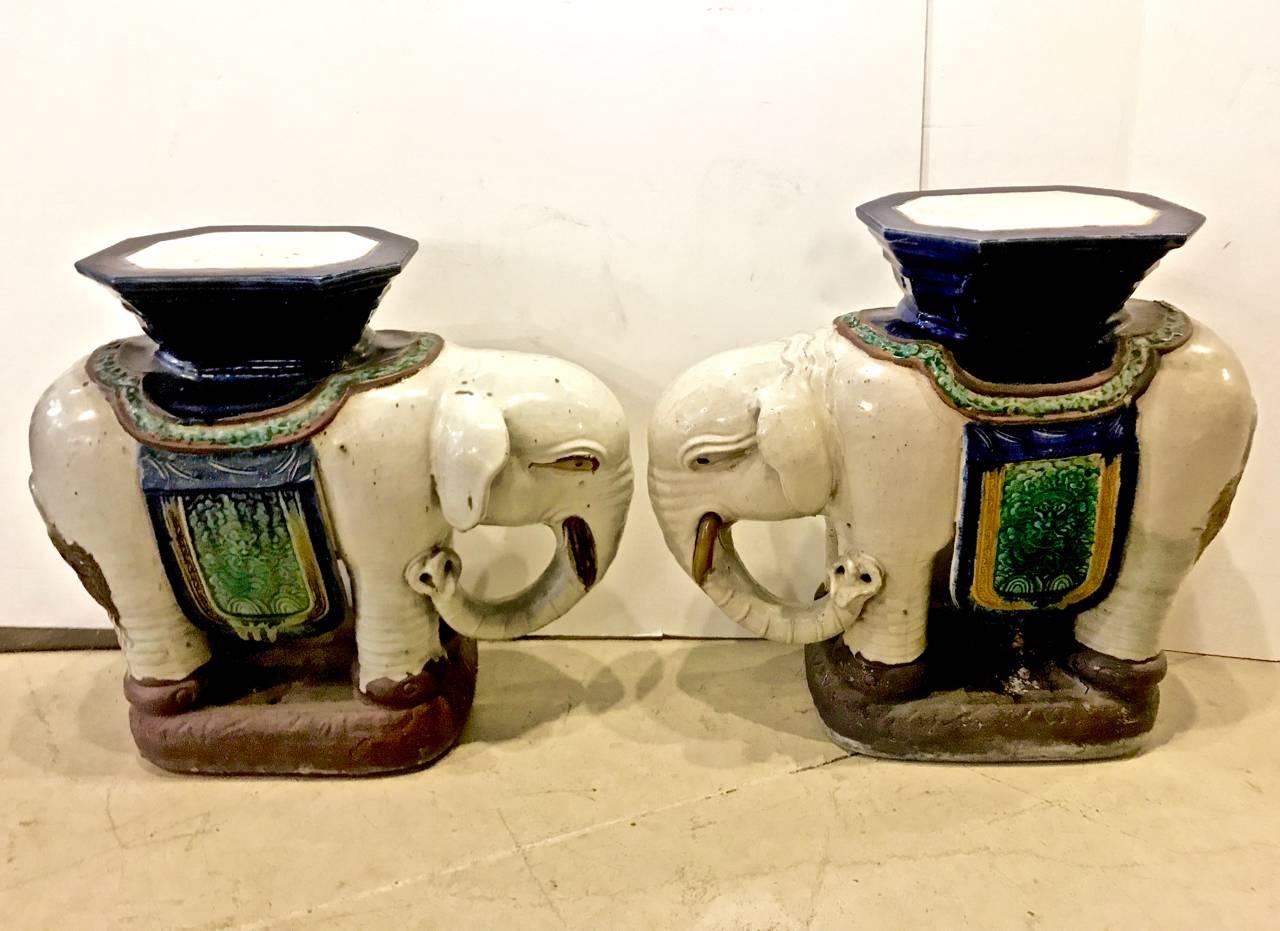 This is a great pair of vintage circa 1960s, Asian elephant garden seats. The elephants are off-white, heavily potted and are adorned with cobalt blue and mottled green draping. Although the elephants are a matched opposing pair, one elephant is 1/2