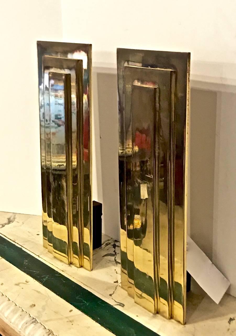 Stunning pair of Moderne andirons. The andirons are designed with a set of three very heavy stepped polished brass plates. These andirons would also make exceptional lamp bases.