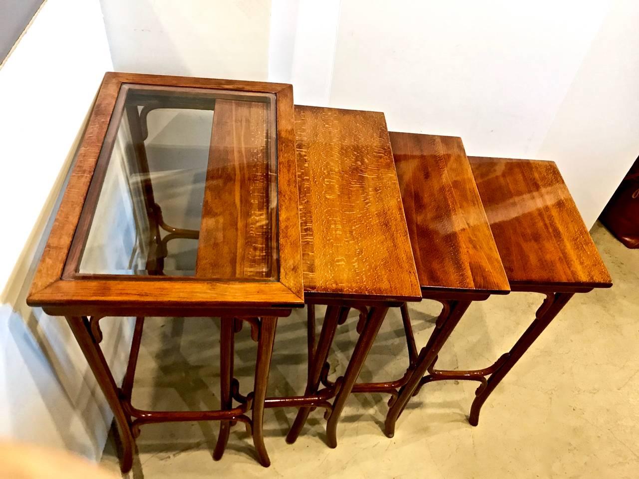 This is a beautiful set of quartetto or four nesting tables in the style of Thonet. The tables have been recently refinished and are in excellent condition. The beveled glass insert on the largest table is a unusual feature leading to the