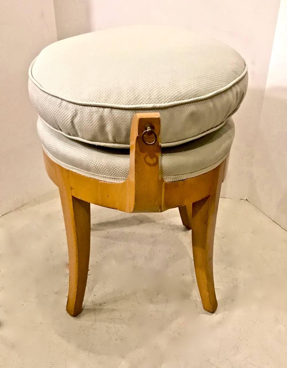 This is a charming French Sycamore, circa 1940s vanity stool of neoclassical/Biedermeier form in the style of Rene Prou. The out scrolling arms combined with the saber legs make the stool and eye-catcher.