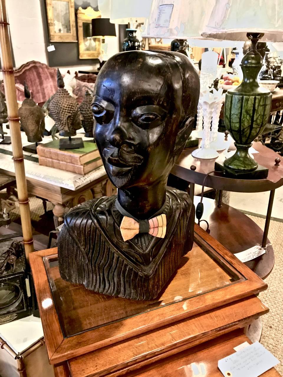 This is an exceptionally well-carved portrait bust of an African man dating to the mid-20th century. The bust is carved from a single piece of mahogany; the artist has captured the sitter's character. This gentleman came with his bow tie; so we have