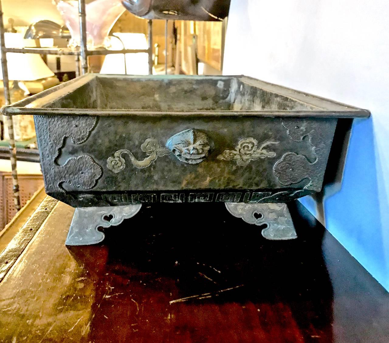 This is a large bronze Hibachi or bulb planter that dates to the later Japanese Edo Period. The bronze hibachi is detailed with applied dragon and flaming pearls, as well as dragon masks to the ends. The rectangular bronze pan is mounted on brass
