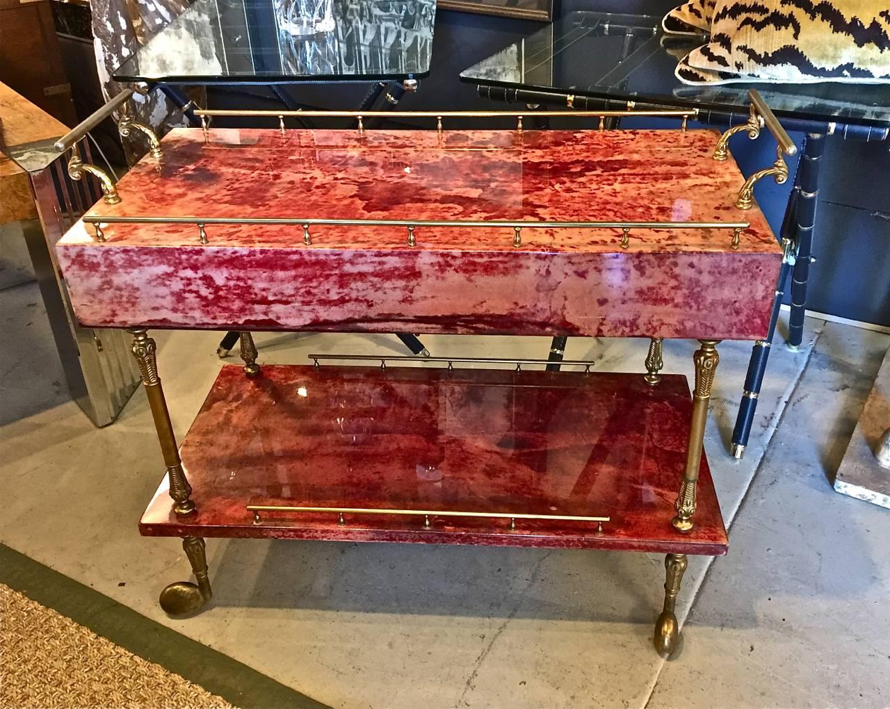 This is an outstanding example of the iconic Aldo Tura bar cart. The cart features an unusual and stunning red lacquered parchment (goatskin) surface. The two end drawers used to store bar essentials are also a unique feature. The cart is in overall