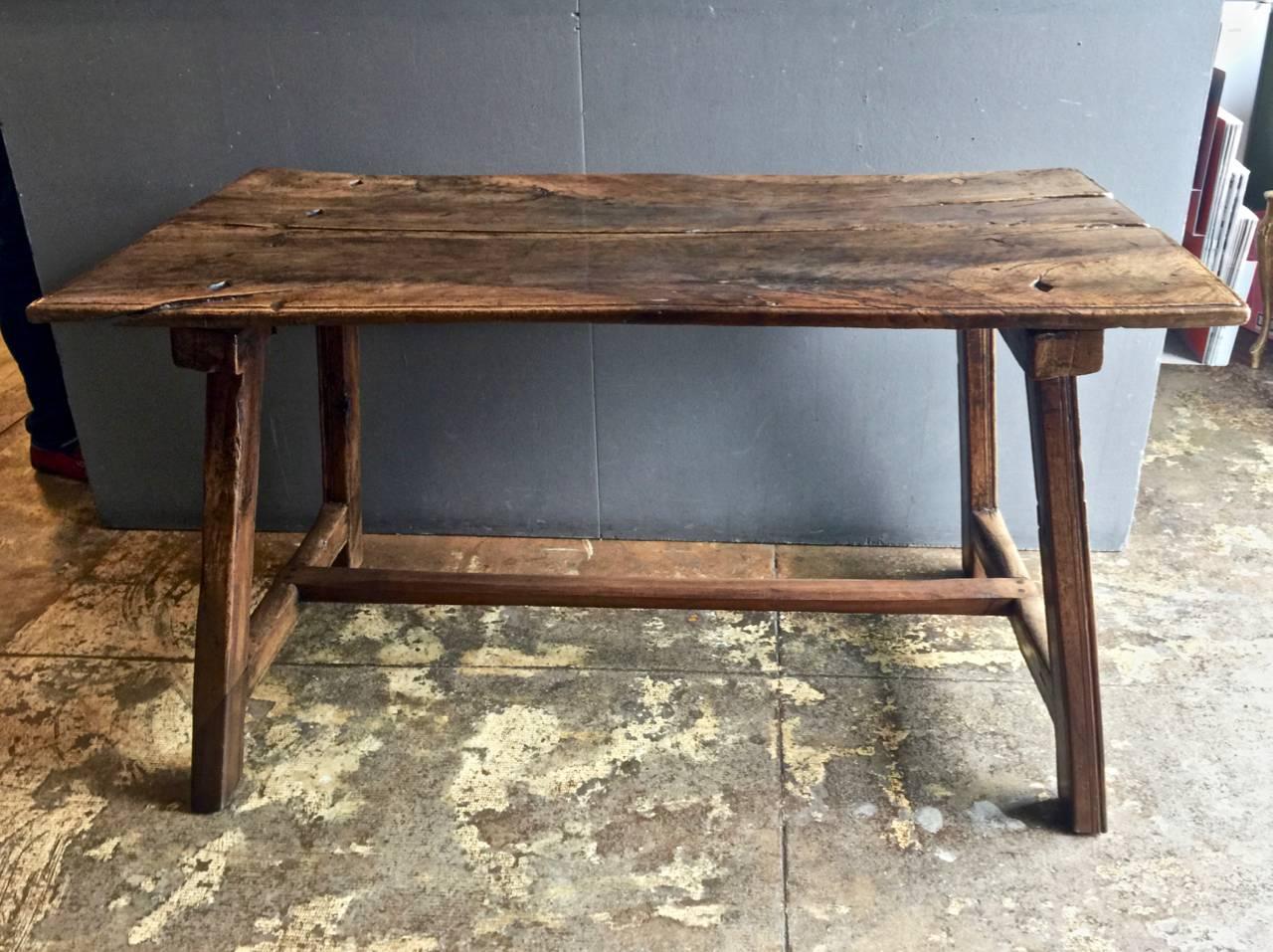 This is a beautifully patinated late 17th century Spanish trestle table. The table appears to retain its old soul-filled highly desirable original surface. The solid two board walnut top is secured to the leg supports with its original heavy