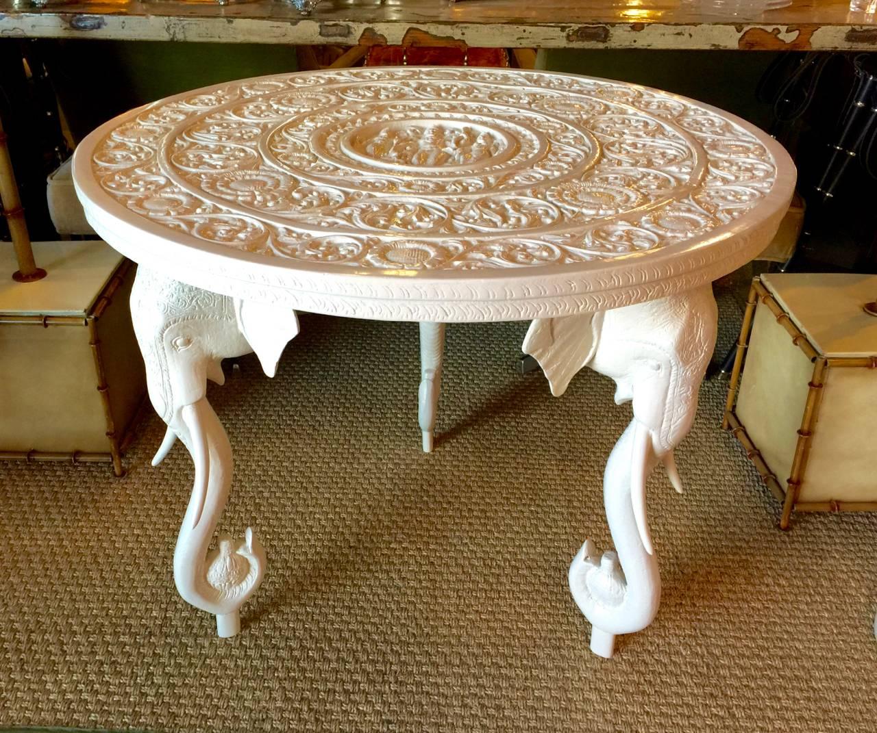 This is a stunning elephant table by Gampel-Stoll that was created in the 1970s. The top of the table is carved wood and the elephant head supports are composition. The table is newly lacquered in a creamy white; there have been restorations to the