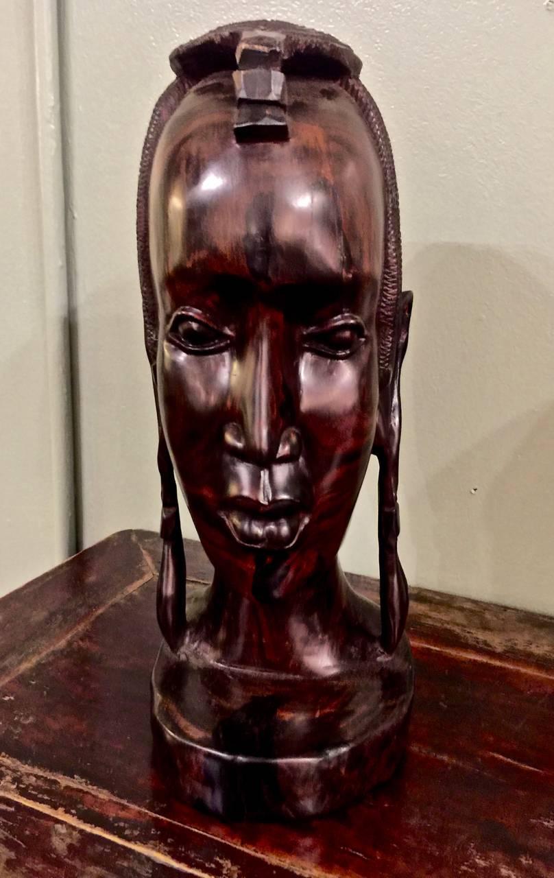 This is a stunningly beautiful African carved ebony female bust. The figure has been carved from a solid ebony trunk; the fine carving of this very dense wood reveals the skill of the carver who has chosen to highlight the deep graining of this