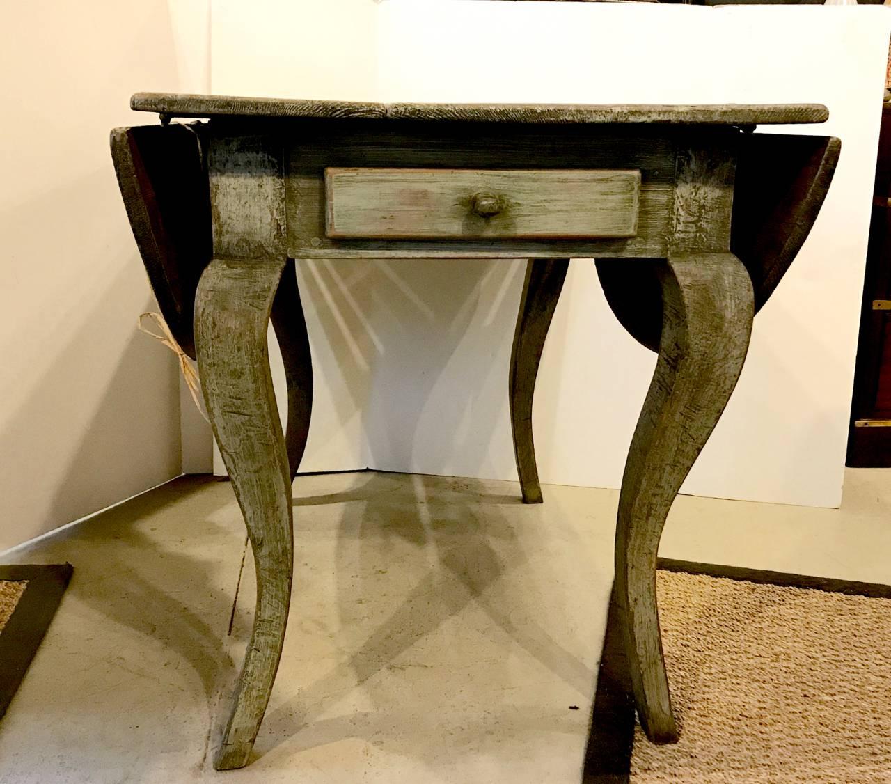 This is a wonderful 18th century drop-leaf table. All elements except the painted surface appear to be original. The curvy sexy Baroque legs and the old forged iron hinges give this table lots of character. With the drop sides up, the table is a