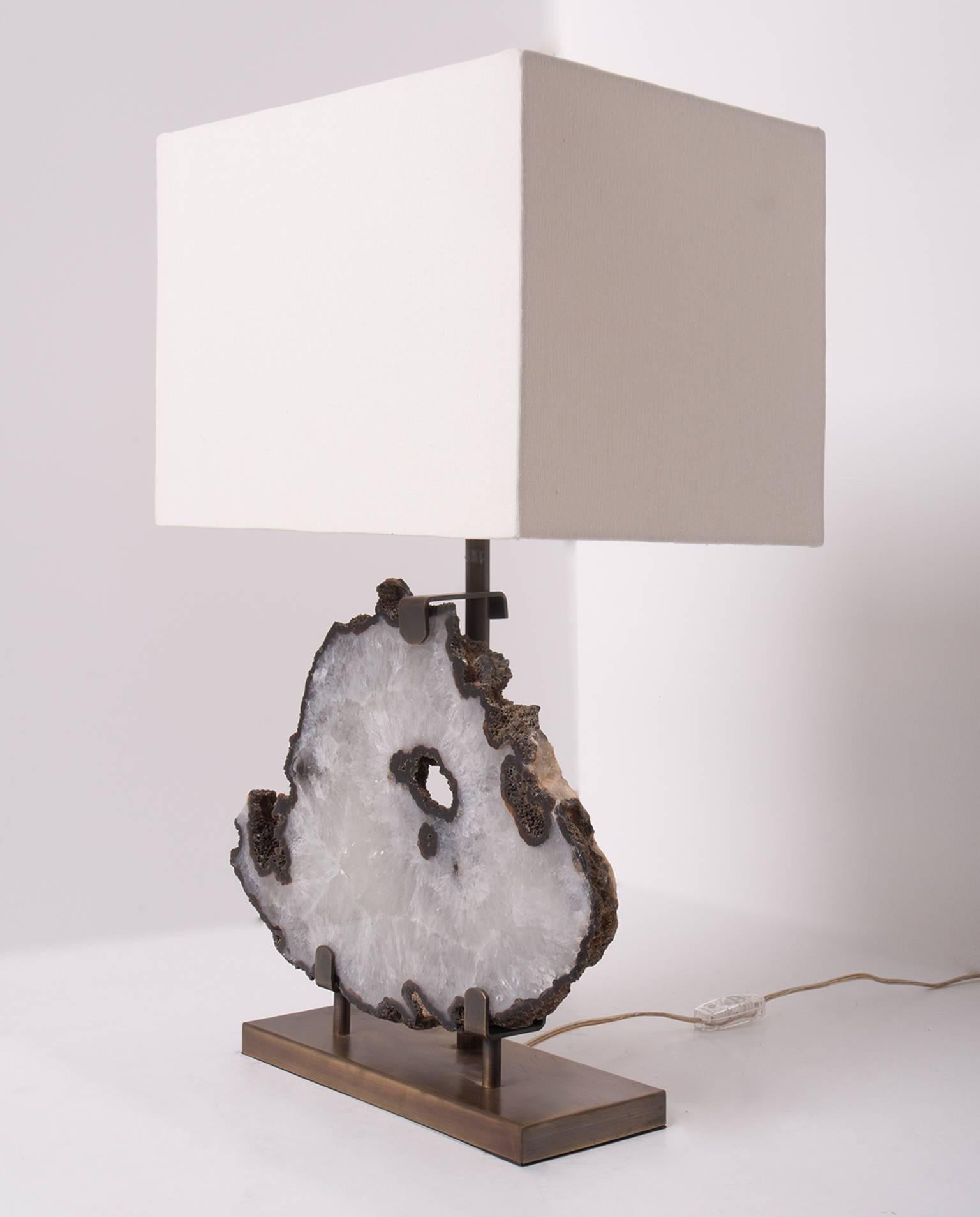 This table lamp is made from an agate slab from Brazil, it has a combination of colors surrounding the white center. It has hints of blue, grey and brown. 

Agates are formed in rounded nodules, which are sliced open to bring out the internal