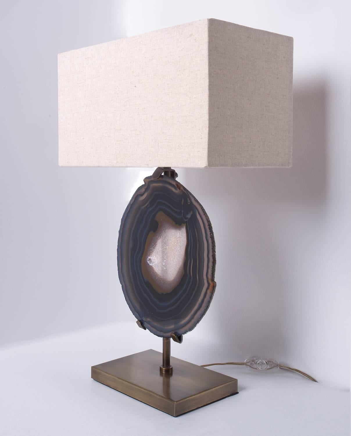 This table lamp is made of an agate slab from Brazil, it has a combination of colors surrounding the white centre. It has hints of blue, grey and brown.

Agates are formed in rounded nodules, which are sliced open to bring out the internal pattern