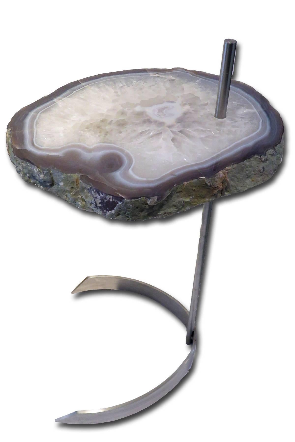 This agate slab forming a side table or cocktail table, is from Brazil and has a combination of colors surrounding the white center with hints of blue, grey and brown. 
Agates are formed in rounded nodules, which are sliced open to bring out the