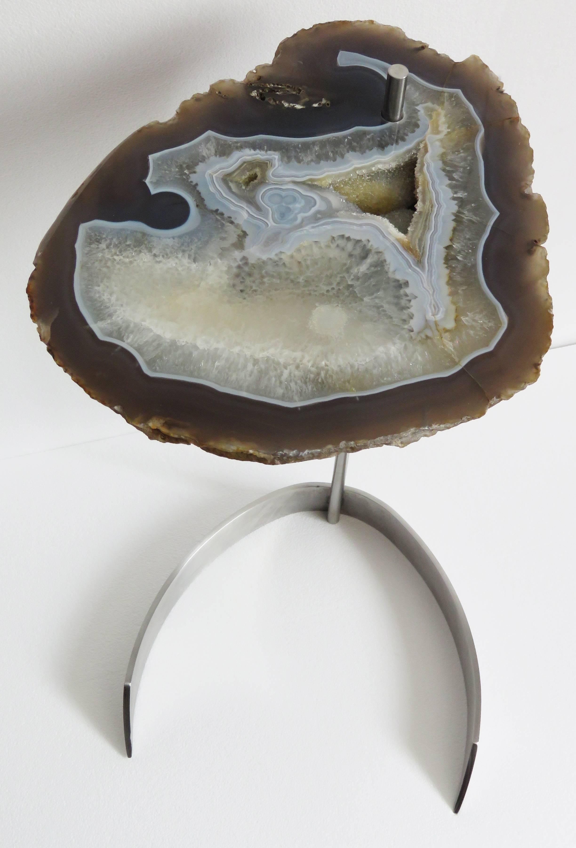 This agate slab is from Brazil, it has a combination of colors surrounding the white center with hints of blue, grey and brown. 
Agates are formed in rounded nodules, which are sliced open to bring out the internal pattern hidden in the stone.