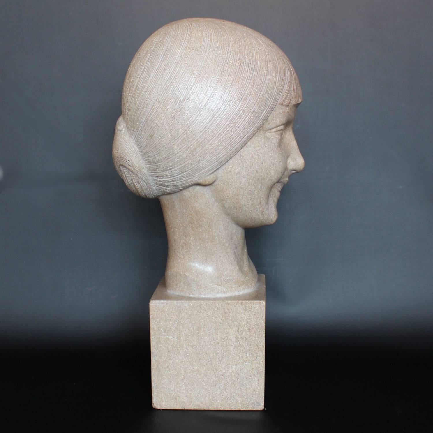 An Art Deco, stone carved sculpture of a smiling young lady, set over an integral plinth. Original dedication plaque to rear.

Signed L. Doré and dated 1924.
 