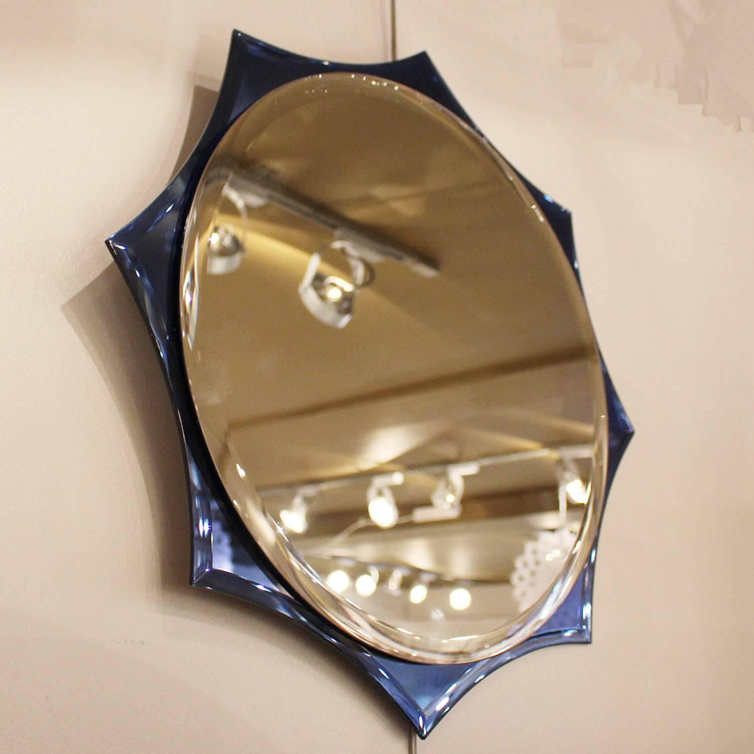 A wall mirror with shaped sides by crystal-Art of Turin. Circular, bevelled, central mirror float set over a bevel edged, blue glass frame.
 