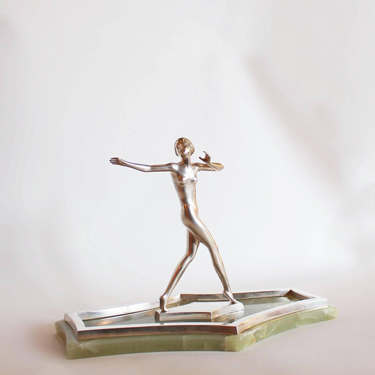 An Art Deco, silvered bronze figure of a young lady in stylised dance pose. Set on an integral silvered bronze base, over a shaped plinth of green onyx and silvered bronze. Signed Lorenzl to base.
 