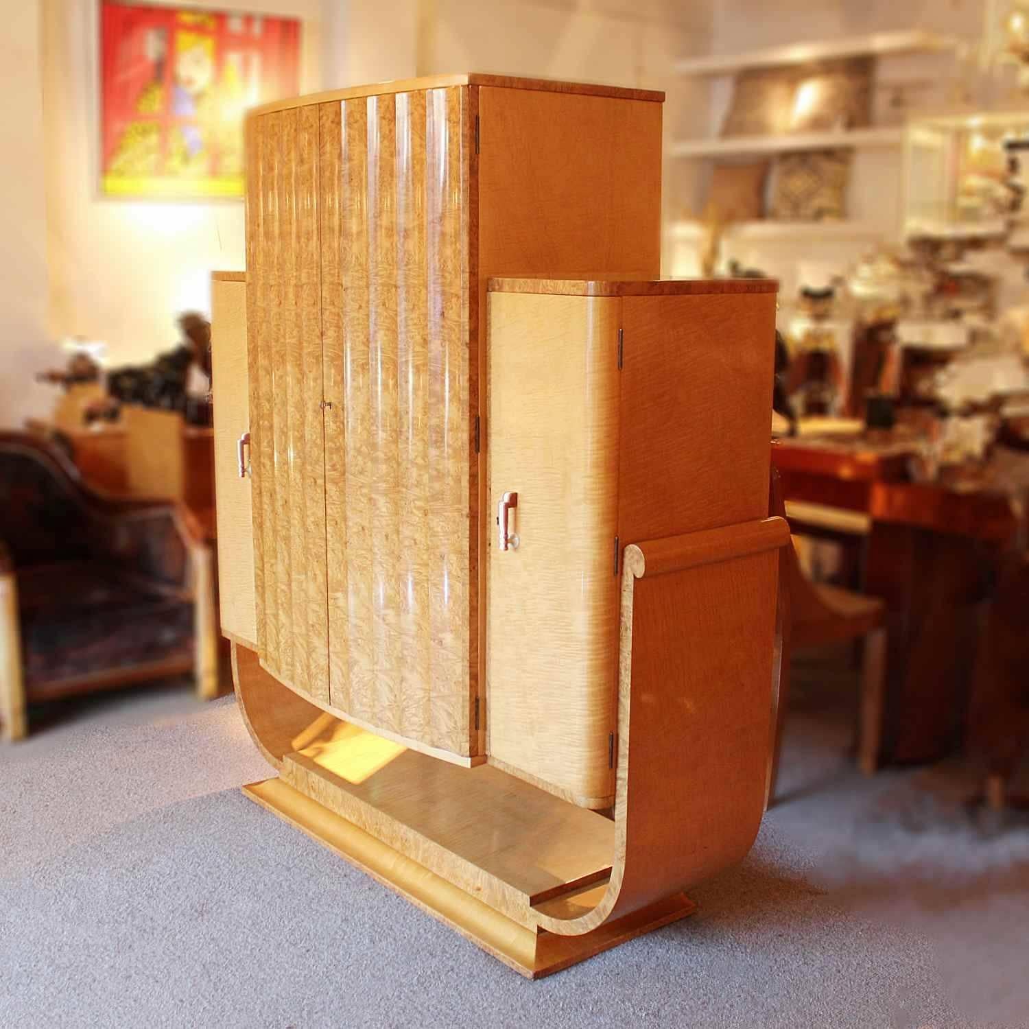 An Art Deco cocktail cabinet by Harry & Lou Epstein in burr walnut and satin birch. Fluted front to a mirrored, lit central cabinet. Side, shelved cabinets with original bi-coloured bakelite handles. Set over a u-shaped based.


Dimensions: H 161