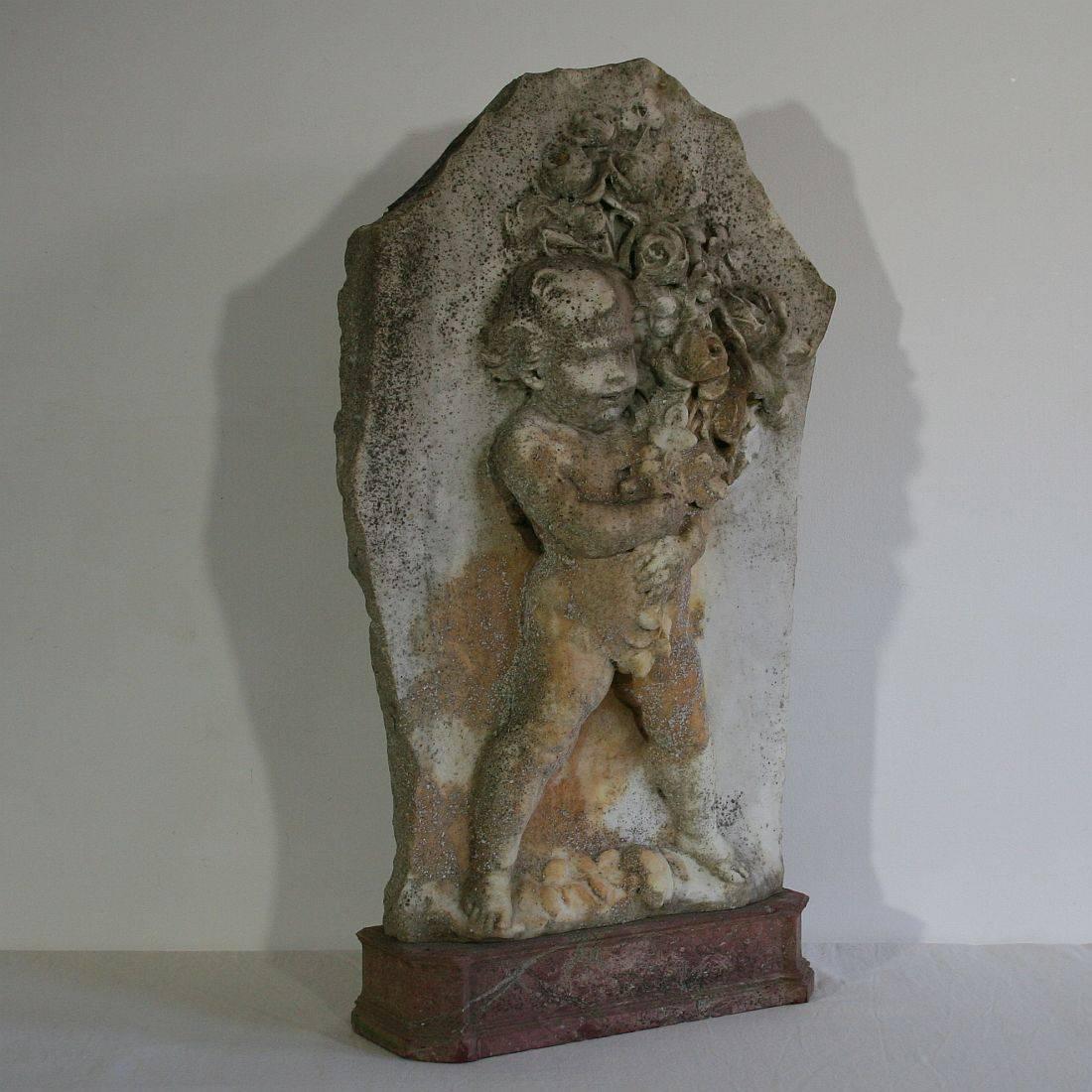 Stunning find. Large marble fragment of a putti holding flowers. Beautiful weathered and once placed on this great piece of red marble.



 