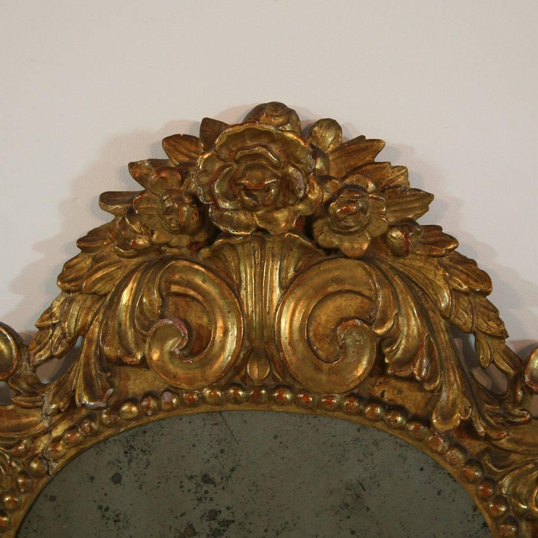 Rare Italian Baroque mirror with nice bouquet of flowers. Although the frame was once broken and this mirror had a rough life it is still a beauty, Italy, circa 1750. Weathered, losses and old repairs.