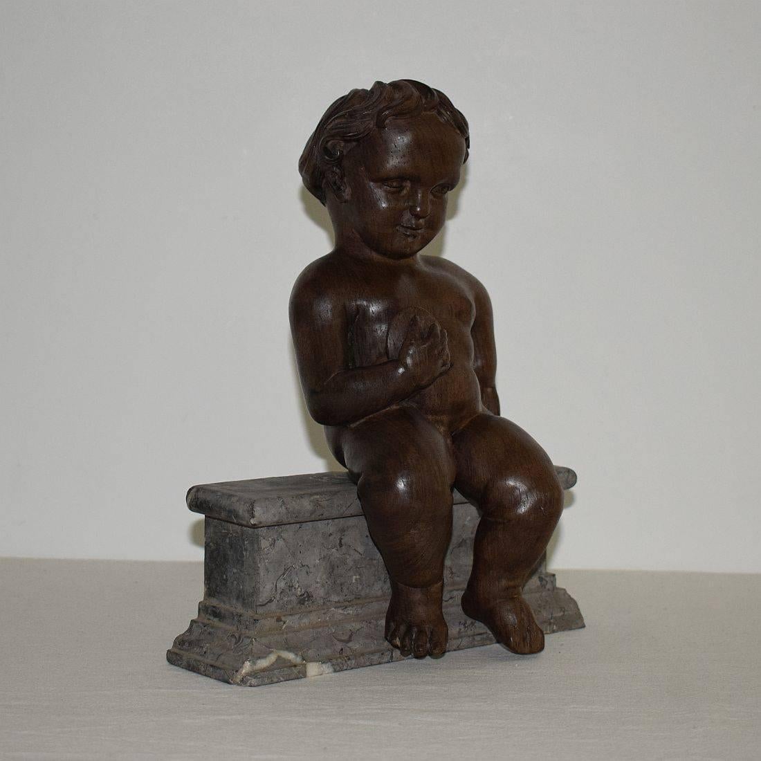 Beautiful hand-carved wooden angel or cherub placed on a weathered marble base. Spain, circa 1700. Weathered, small losses.