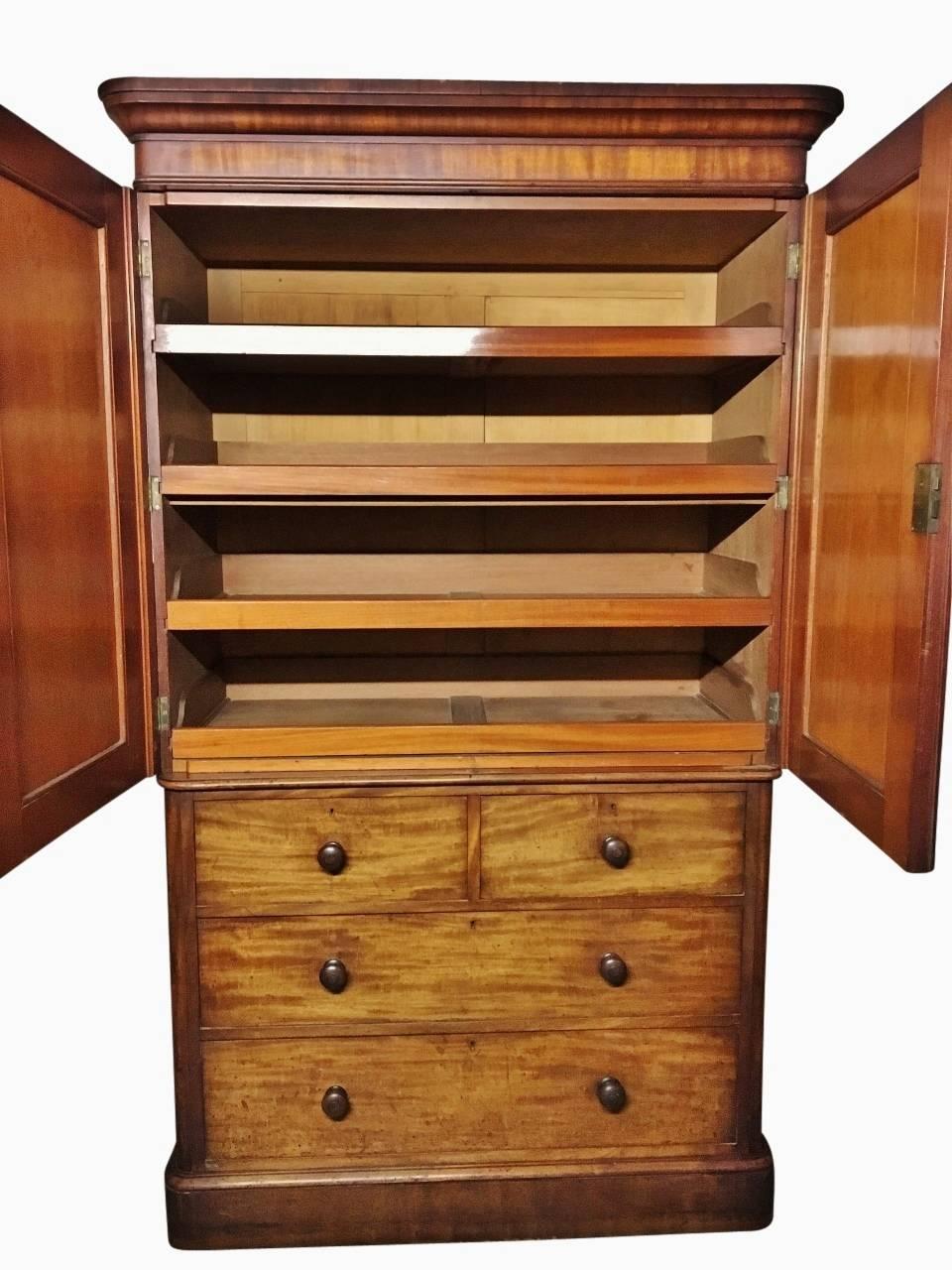 Lovely old Mahogany Linen press from the circa 1860s in very good condition.
There's loads of useful storage and this has four smoothly running drawers of good depth.
The top section has well figured panelled doors enclosing four sliding trays,