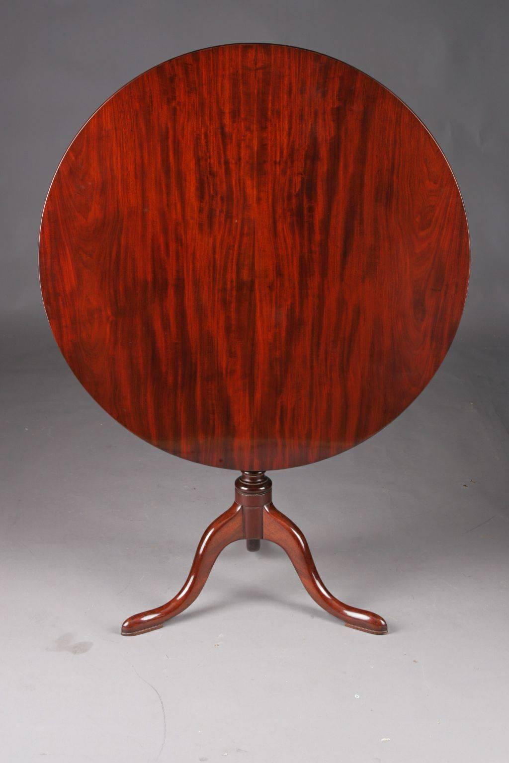 Rare original English Regency folding table or tripod table 18th-19th century.
Through and through massive mahogany. Slim ballroom shank, of which extending three curving legs in so-called pillow-feet. Two straight bars as support for round folding