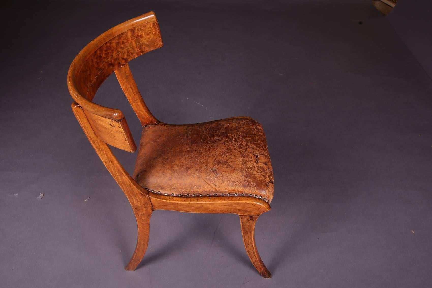 Chair of the Greek antique. 
Solid wood. The striking shape with the wide-legged saber legs and the encircling backrest board was rediscovered in classicism, circa 1800. In this specimen, however, the pure basic form of the Klismos still exists. It