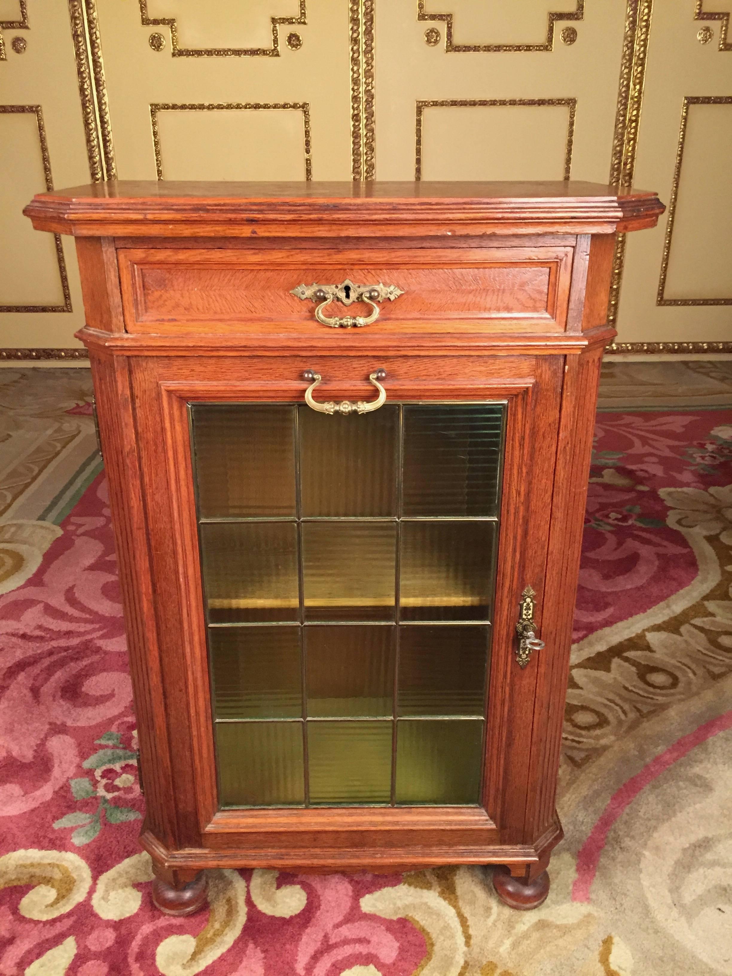 Solid wood, glazed, slightly greenish front as well as a drawer, lockable.
Slightly overhead cover plate.


(D-76)