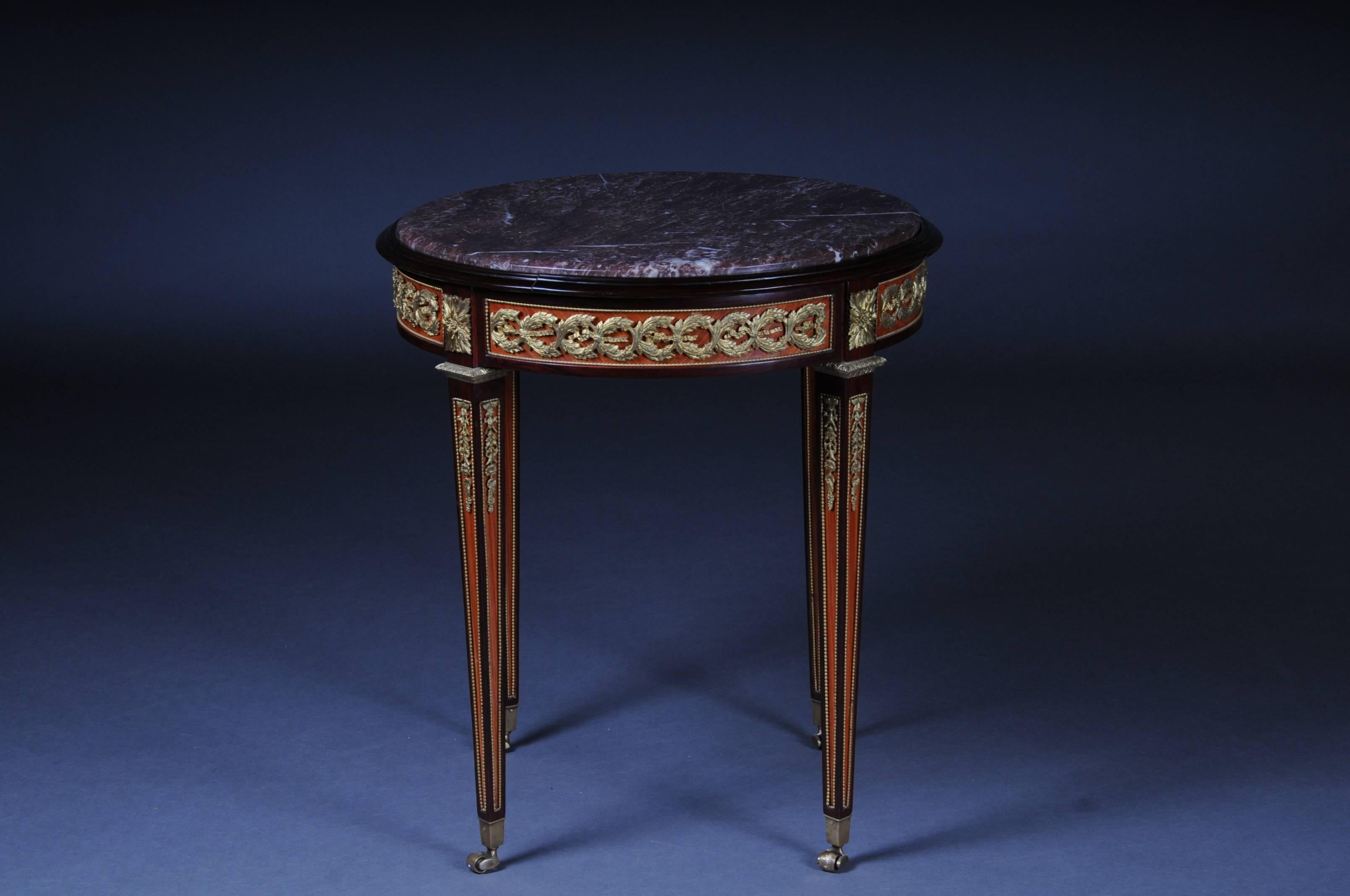Classicist side table. Solid beechwood. Top in mottled marble edged in profile frame. Frame with finely engraved bronze, ending on brass-bound, tapering square legs in sabots with rollers. Solid wood and worked by hand. Beautiful patina, with