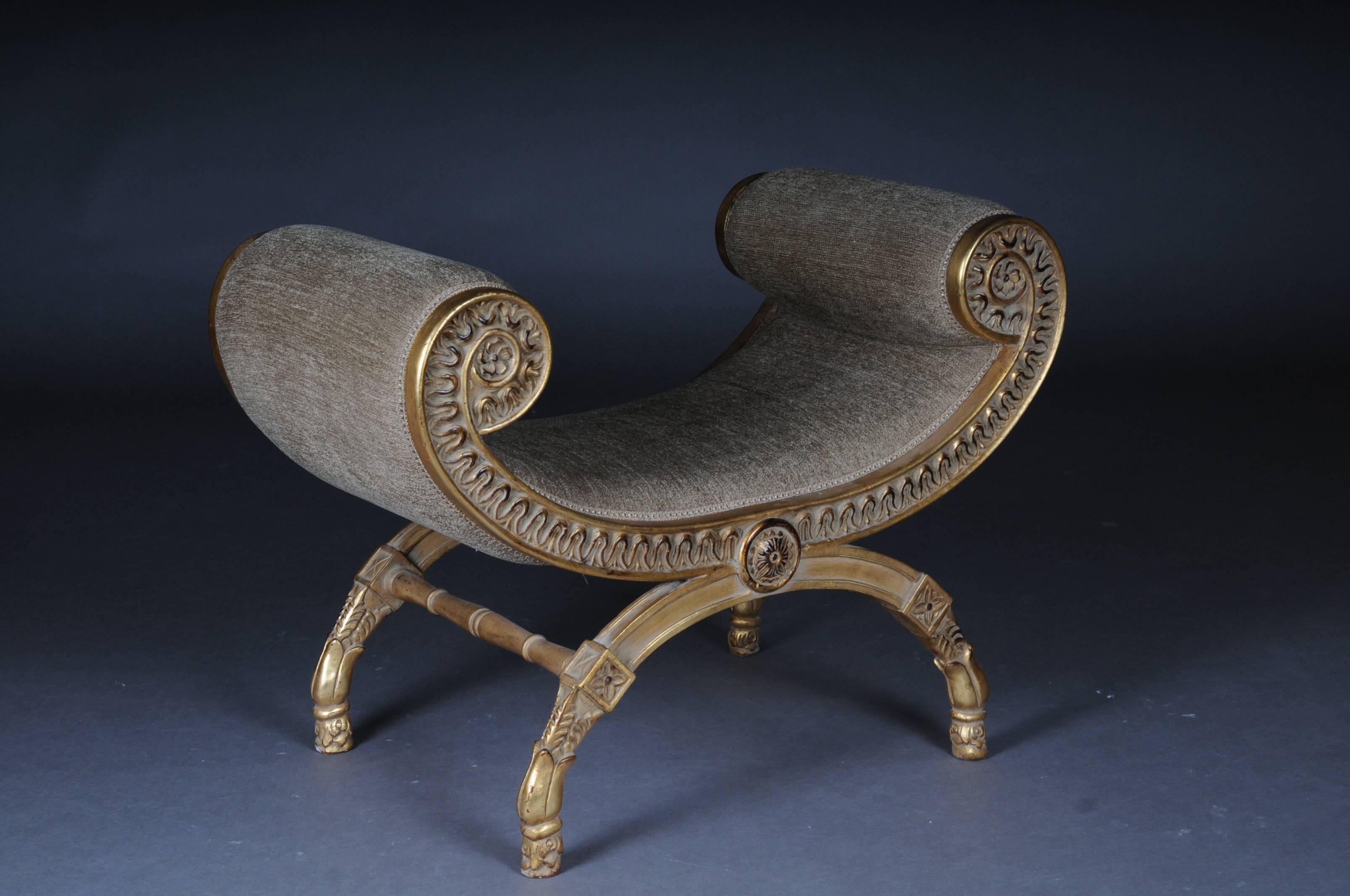 Solid beechwood, finely carved and set. Armrests ending in scrolled volutes. Semicircular frame on four scissor-shaped legs. Below connected by appropriately curly, strongly profiled webs. The seat is finished with a historical, Classic upholstery.