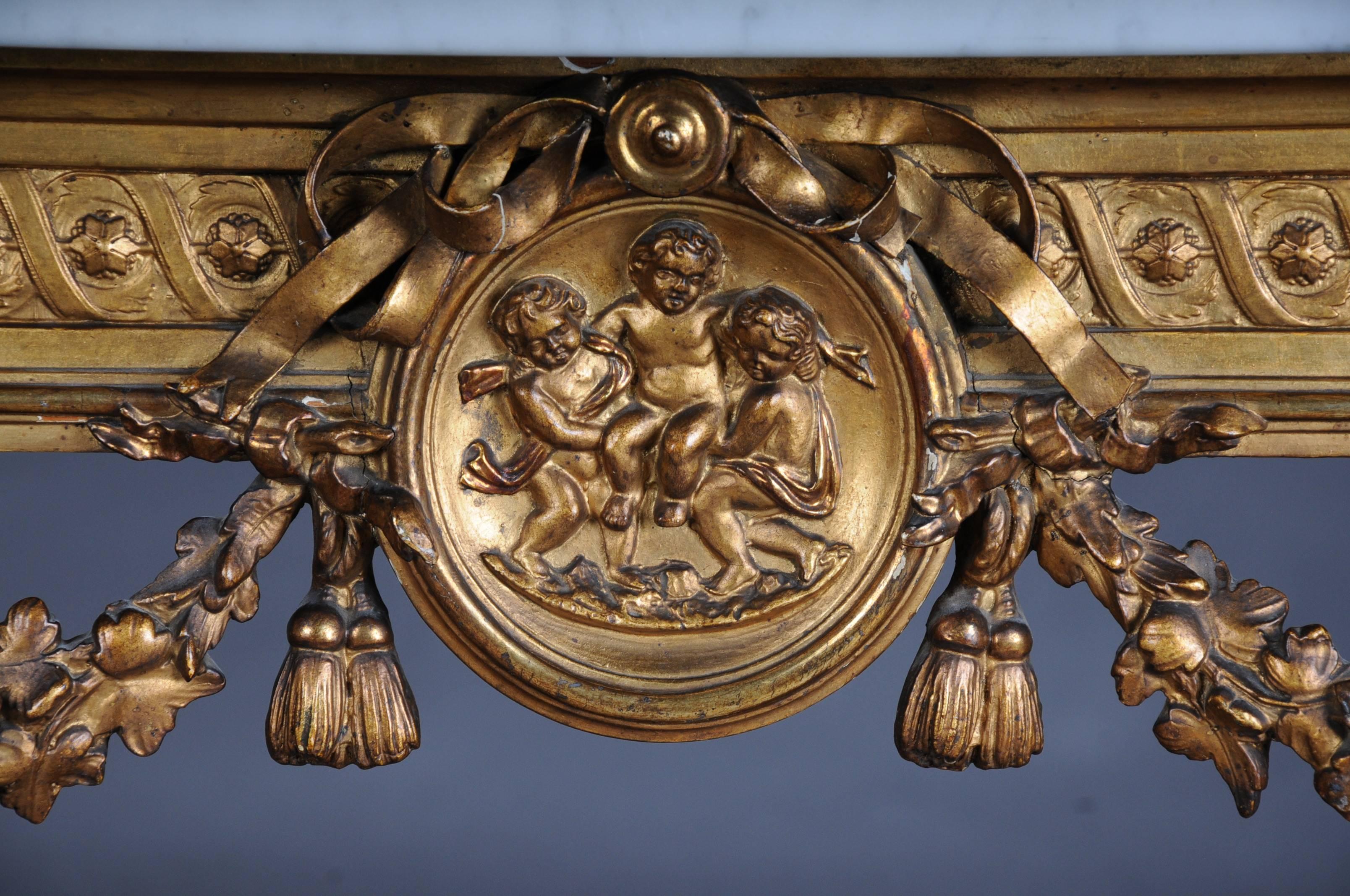 Console. Wood, gilded. Richly carved frame with fluted pillar legs. On bracing urn vase with garlands and cherubs. White marble slab, 19th century.


(E-33).