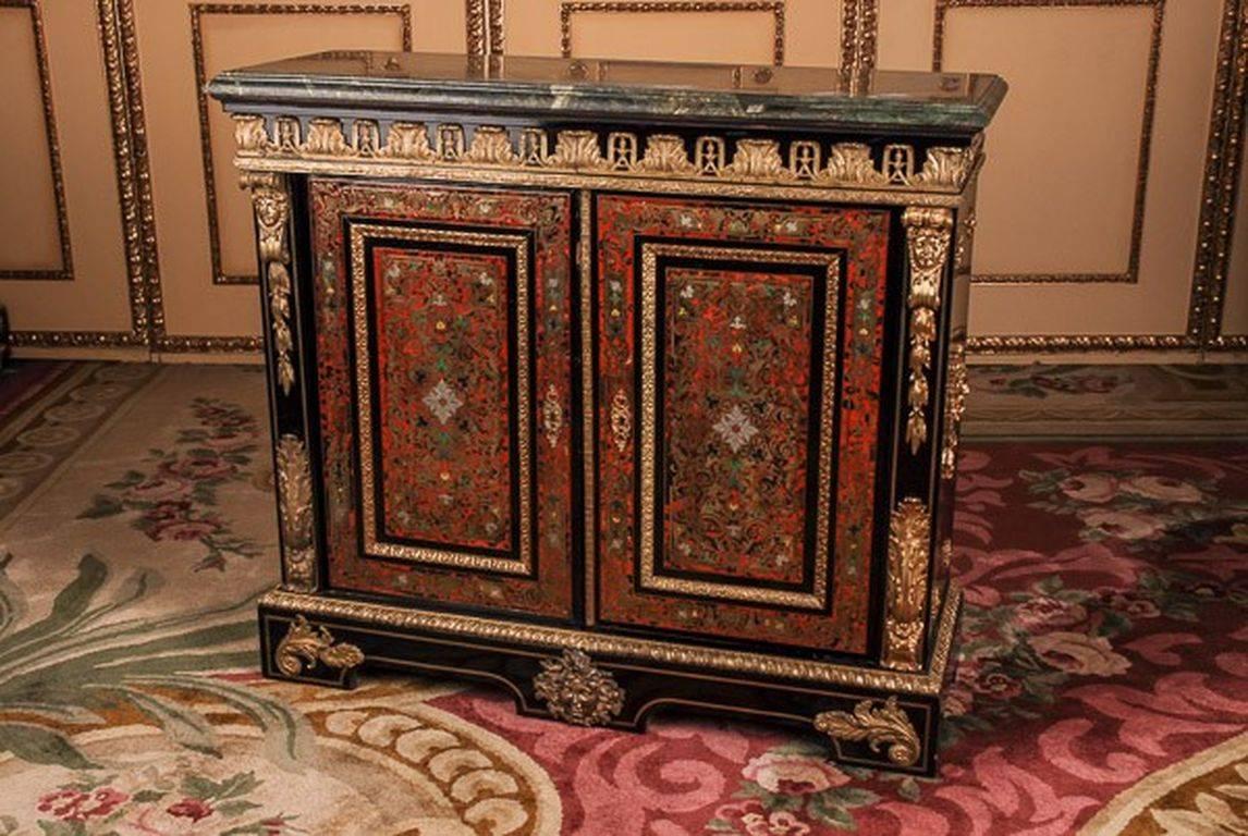 Chased fire-gilt bronze are distinctive and of exceptionally good quality. Ebonized solid oakwood with brass inlays Boulle technique. High-right corpus. In the articulated front, there are two wide doors with an infill filled panel flanked by