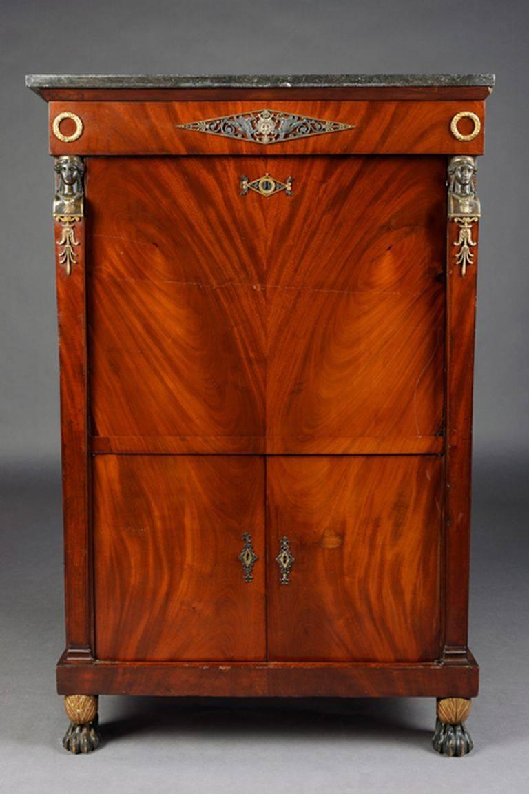 High-quality Cuba mahogany on solid conifers. Architecturally arranged front. High-rectangular body on pawprints in green. Above the writing table with drawer and below with two wide doors. Straight writing plate, behind it architectural interior