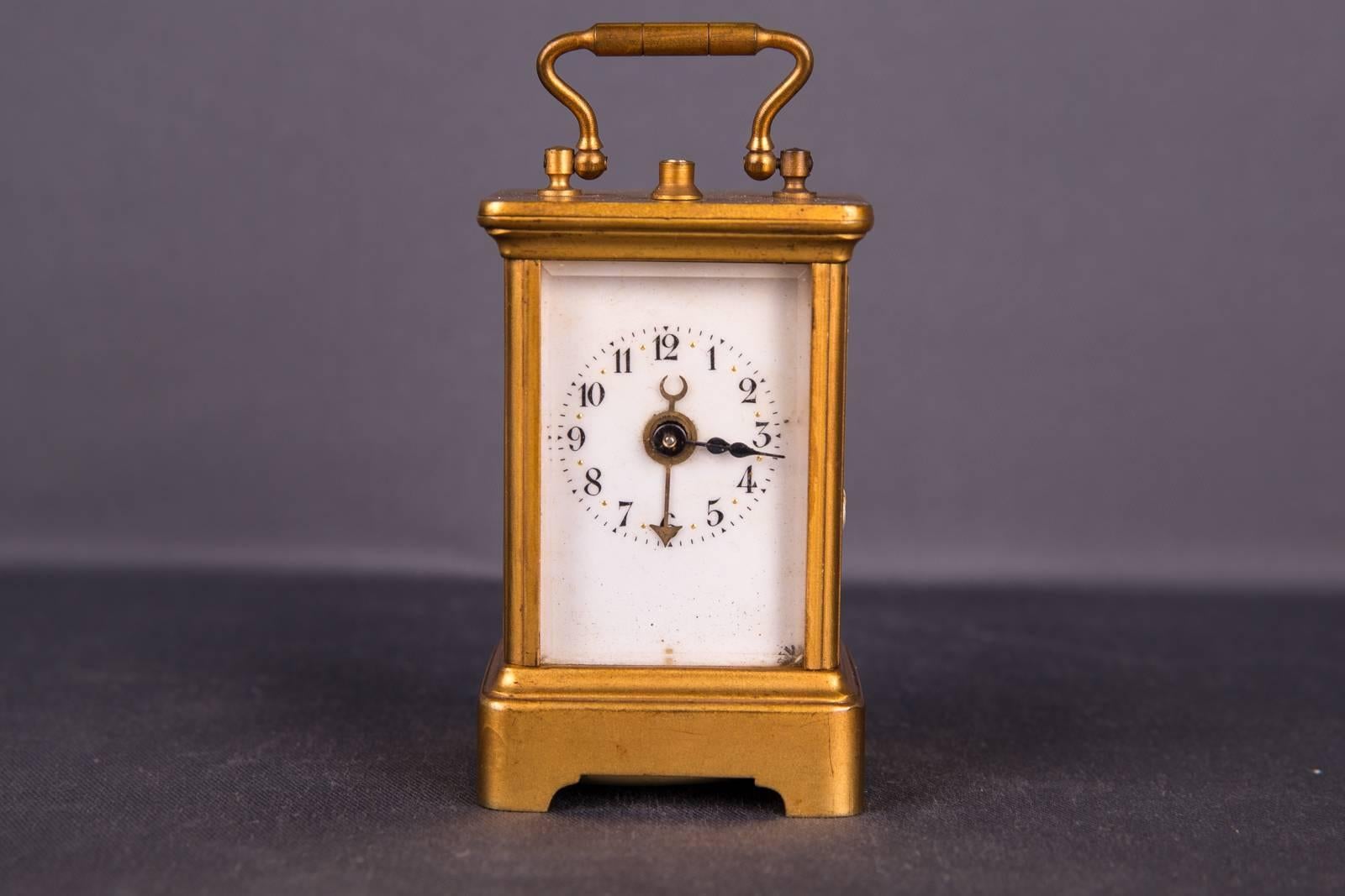 Old clock, brass case roundherum flanked with polished glass. Digit with Arabic / Roman numerals three pointers. Clockwork should be overtaken. Left glass plate at the lower corner minimally beaten.

Clockwork must be repaired.

(R-44).