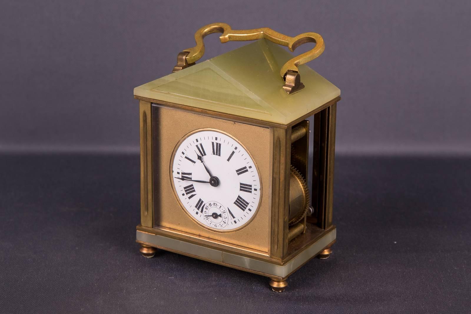 Alte französische Reiseuhr mit Onyx-Applikationen. Quadratisches Dach. Auf der Uhr befindet sich ein gebogener Griff. Uhrengehäuse auf vier kugelförmigen Füßen. Linke Scheibe fehlt. Das Uhrwerk sollte überprüft werden.

(R-45).
