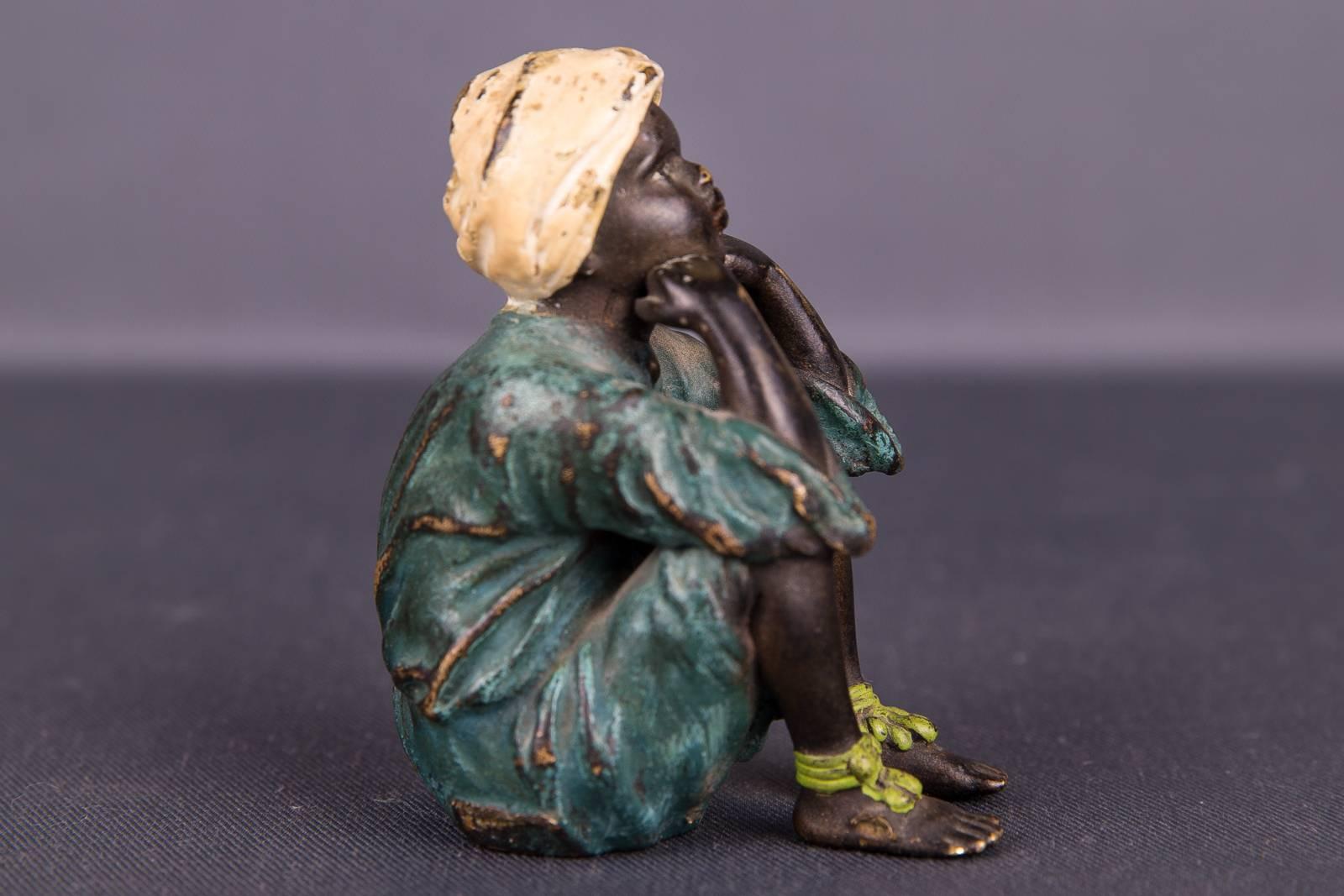 Colored bronze as a small boy in a sitting pose. Blue robe with white turban.
Pronounced fine workmanship in solid bronze.

(V-87).
  
