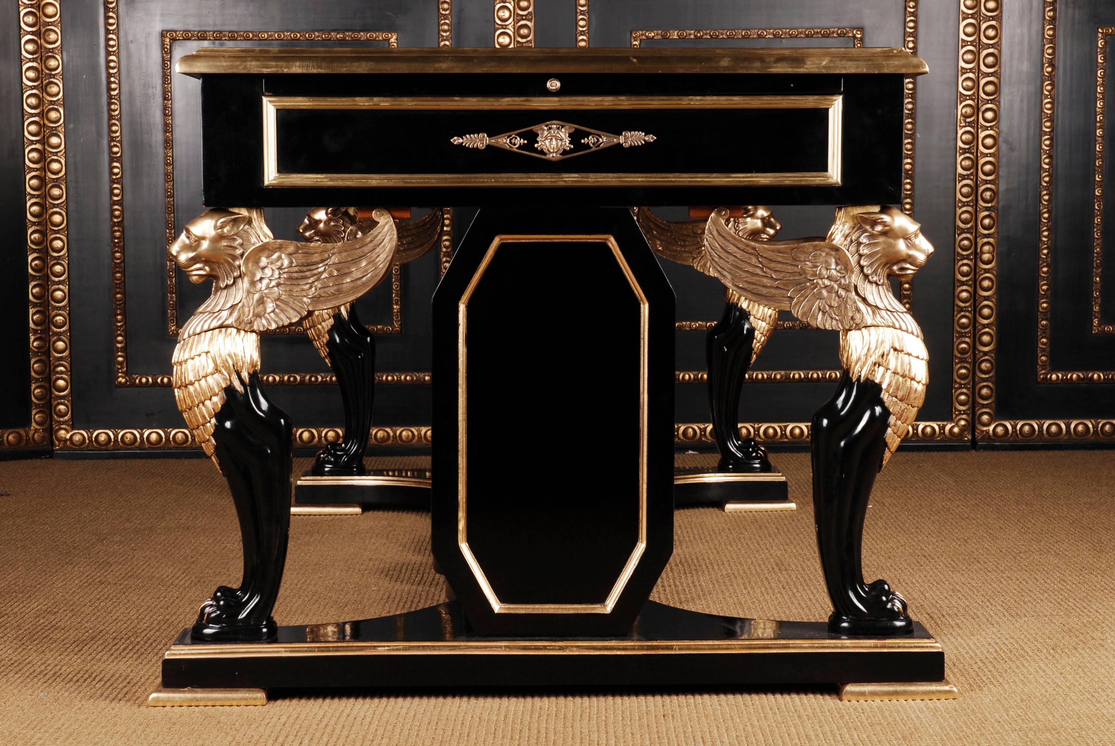Writing table or bureau plat in Empire style after Jacob Desmalter.
Solid, ebonized beech, partially carved and hand-painted. Cutted out pedestal on profiled disc feet. Over which are typically large corner standing winged moulded, prominent Lions