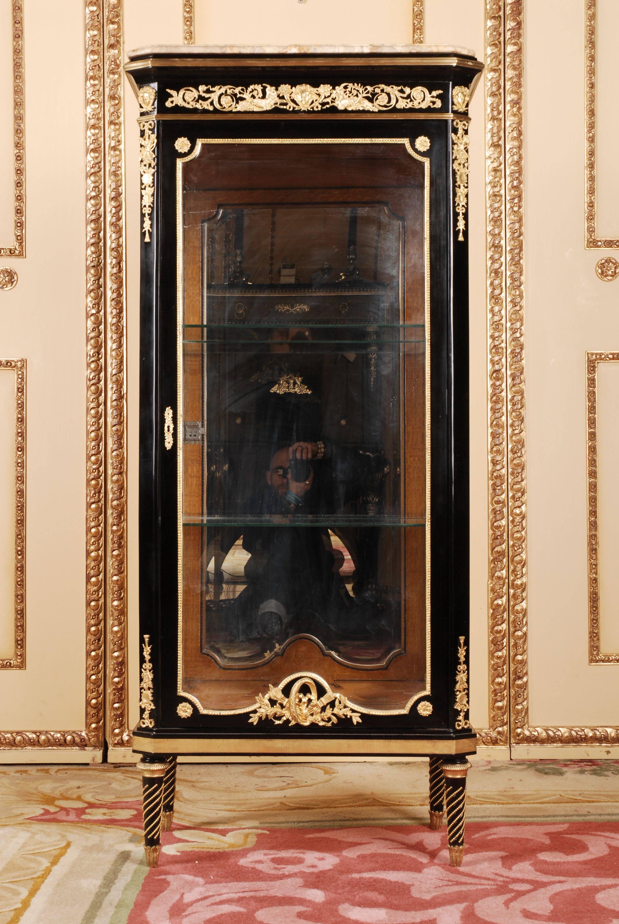Exclusive French Vitrine in Louis XVI style.
Finely engraved and moulded bronze. Solid beechwood. Three sided glassed, one drawered body on conical legs. Profile- framed flecked Marble platter. On the front, corners and sides, classicist