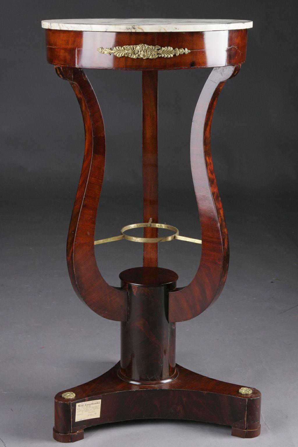Mahogany on solid wood and partly boned. Round leaf with black-and-white interspersed marble, over simple frame and lyra-shaped curly legs on three-sided retracted base plate and disc feet. This form is extremely rare. Decorative bronze