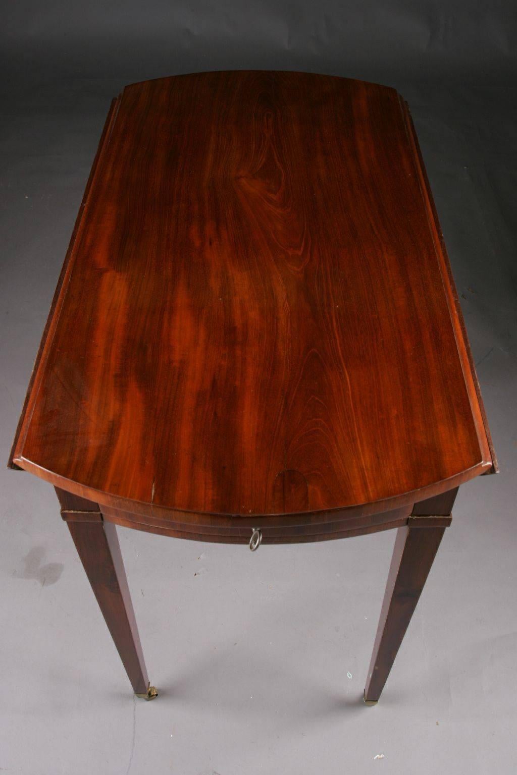 Original Biedermeier folding table or Pembroke table, circa 1825-1830.
Gorgeous mahogany on pinewood. Straight edging base on conical squares in bronze caps with wheels ending. Deep drawer on the side. Slightly protruding tabletop, foldable on both