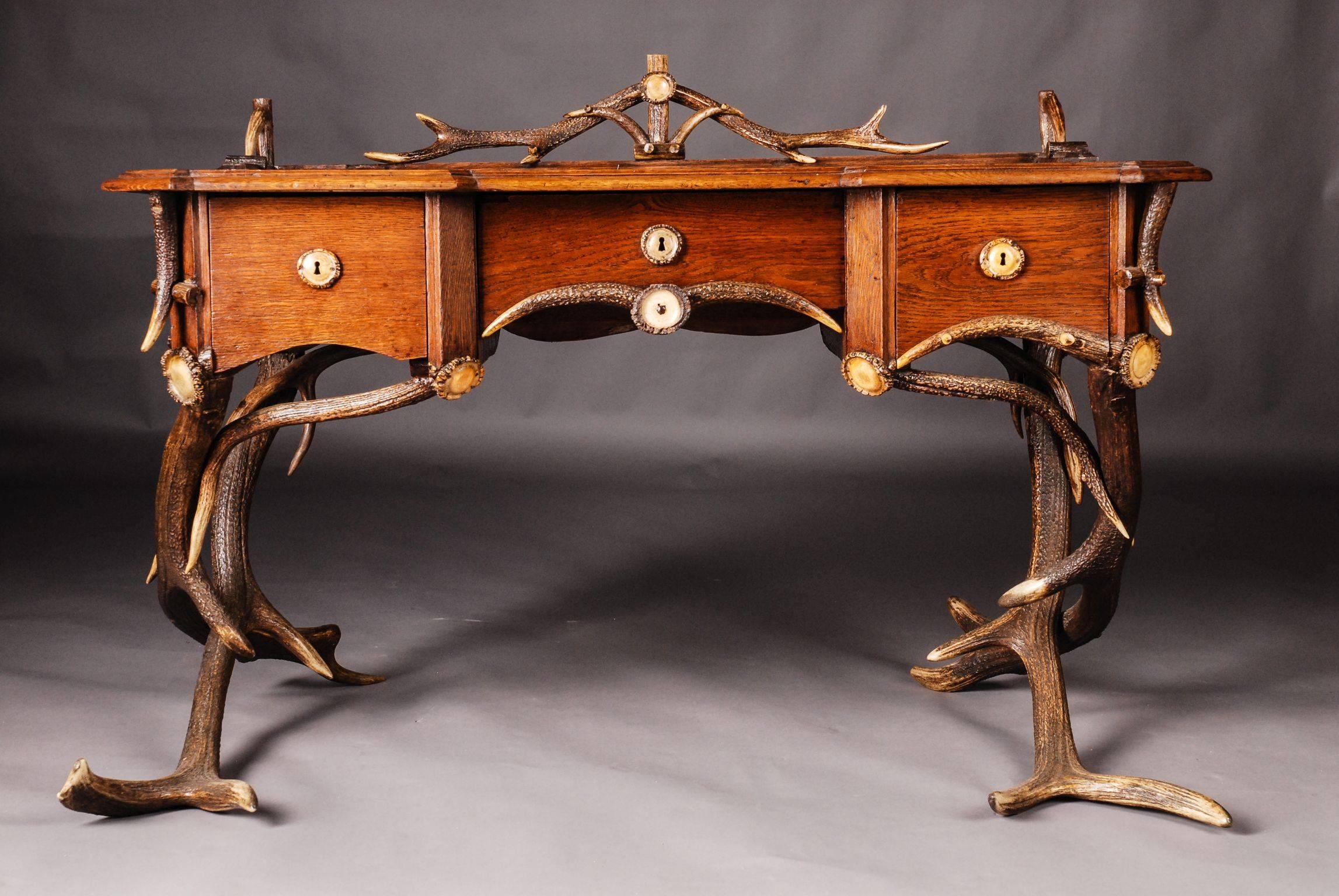 Musealer antique antler desk, circa 1840-1860.
Massive oak body on cross, linked feet. High knee pocket on the front with three drawers of different sizes. Antler decorated top.

Measures in cm:
Overall size height 88 cm, width 127 cm, depth 78