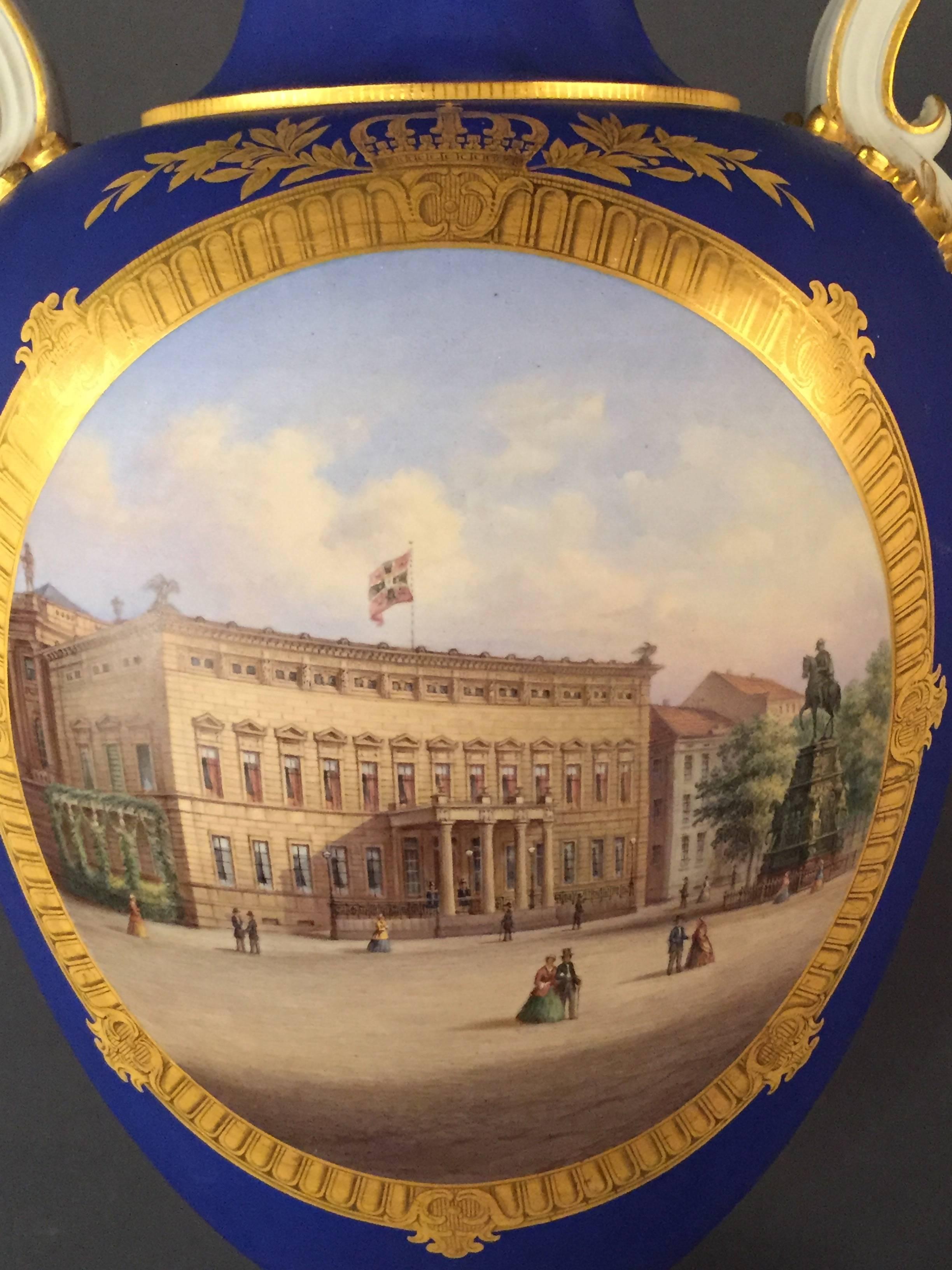 Biscuit porcelain matte blue background. Round picture frame in a crowned gold-framed frame, color-painted view of the Crown Prince's Palace with a statue of Frederick the Great and strollers.
Etched gold contours and gold-rimmed handles.
A spiral