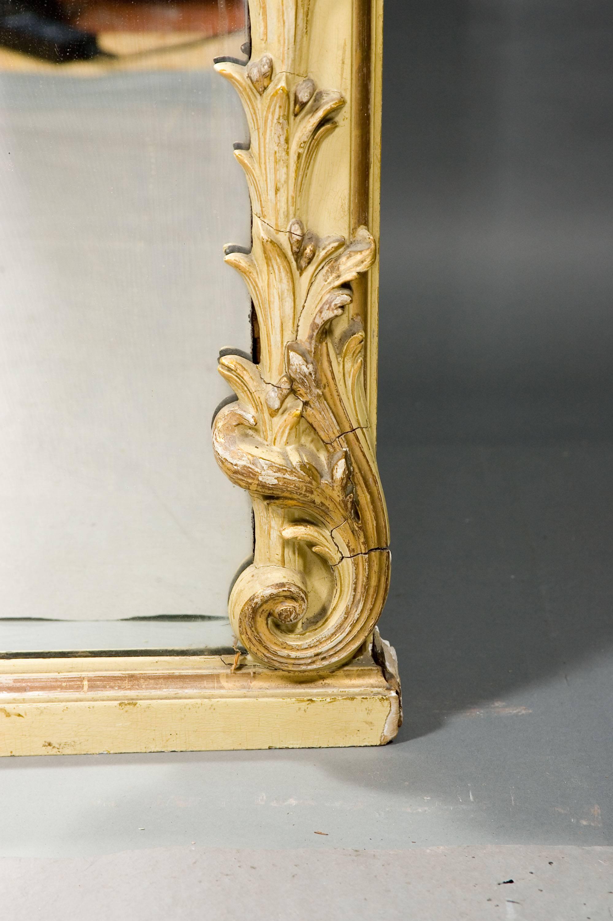 A monumental mirror in the Louis XVI style, circa 1850-1860. Wood and stucco. Poliment gilded and colored. High-angled mirror frame made from acanthus leaves surrounding the circumference. Fully embellished crown of rocaille cartouche and plastic