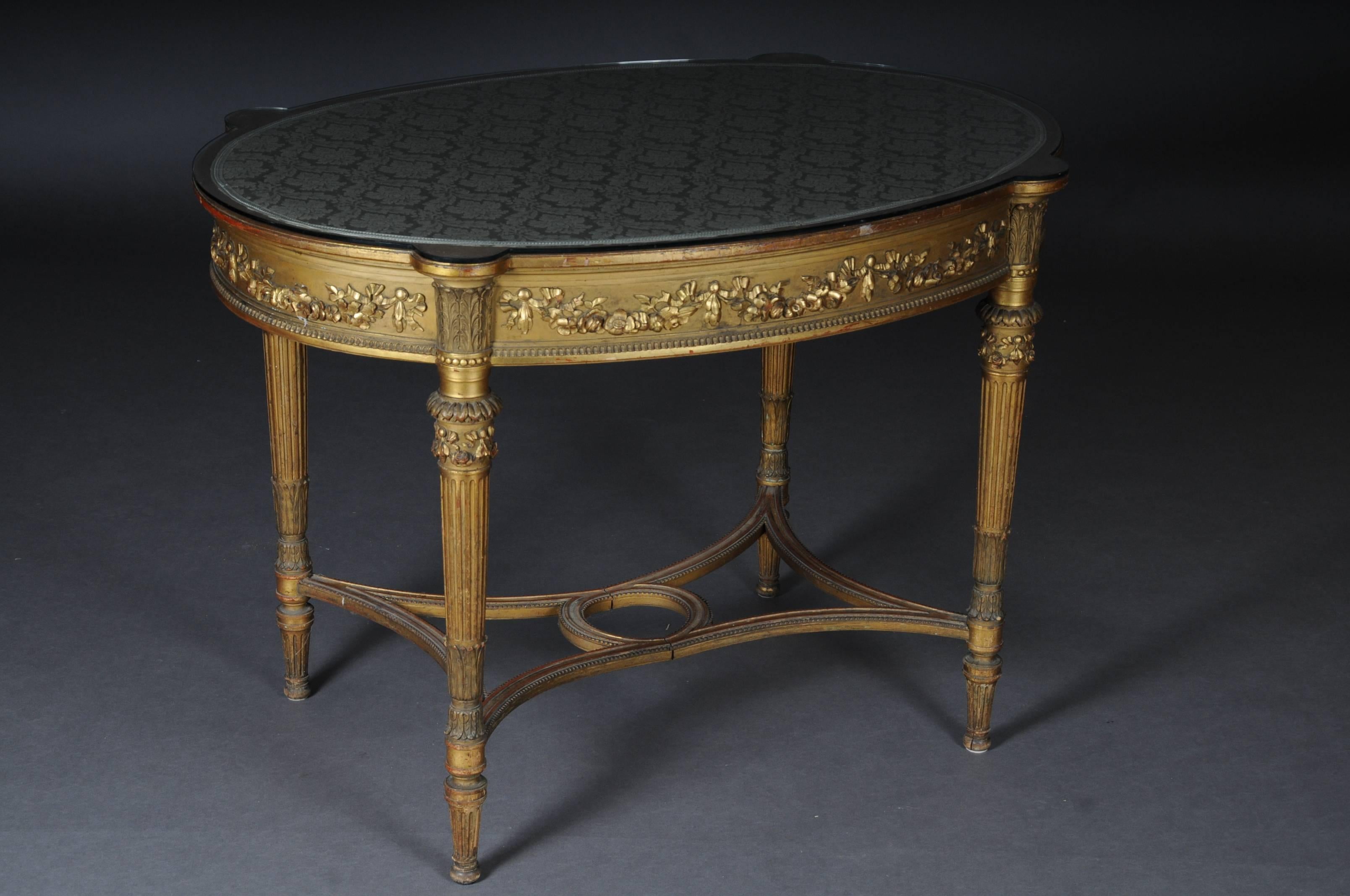 Solid wood carved and gilded. Oval cover plate on fluted, pointed feet crossed with centre bar. Frame with carved garlands.


(A-147).